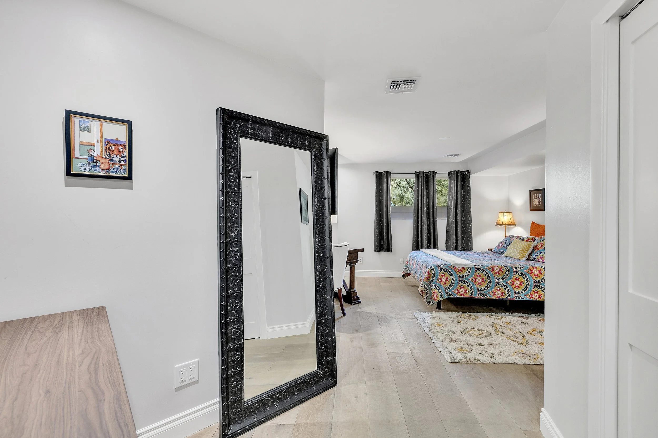 This bedroom in Paradise Valley, AZ features modern decor, a large mirror, and ample natural light, highlighted through professional real estate photography.