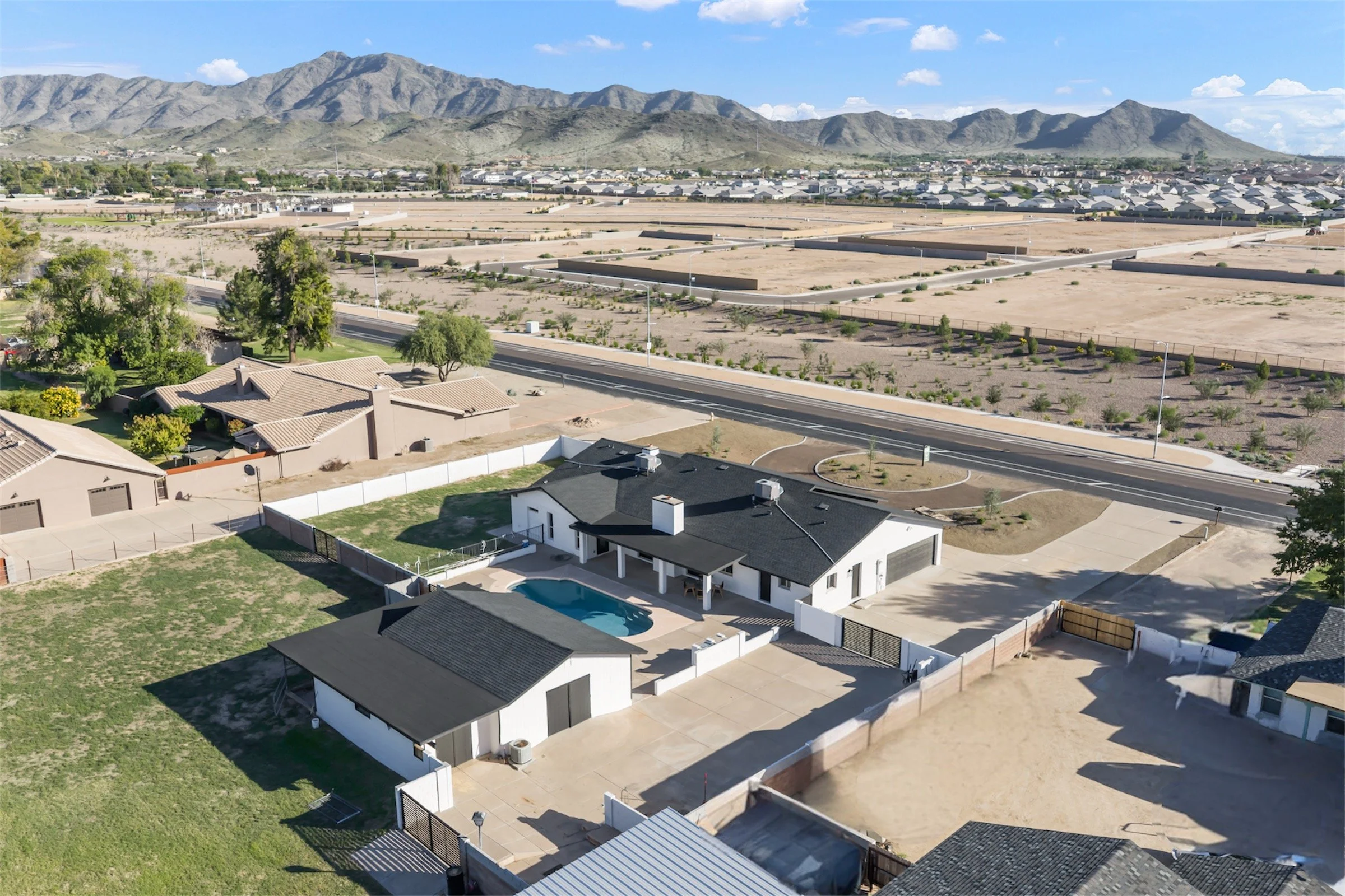 Aerial drone photo showcasing modern home with pool and mountain backdrop in Phoenix, AZ.