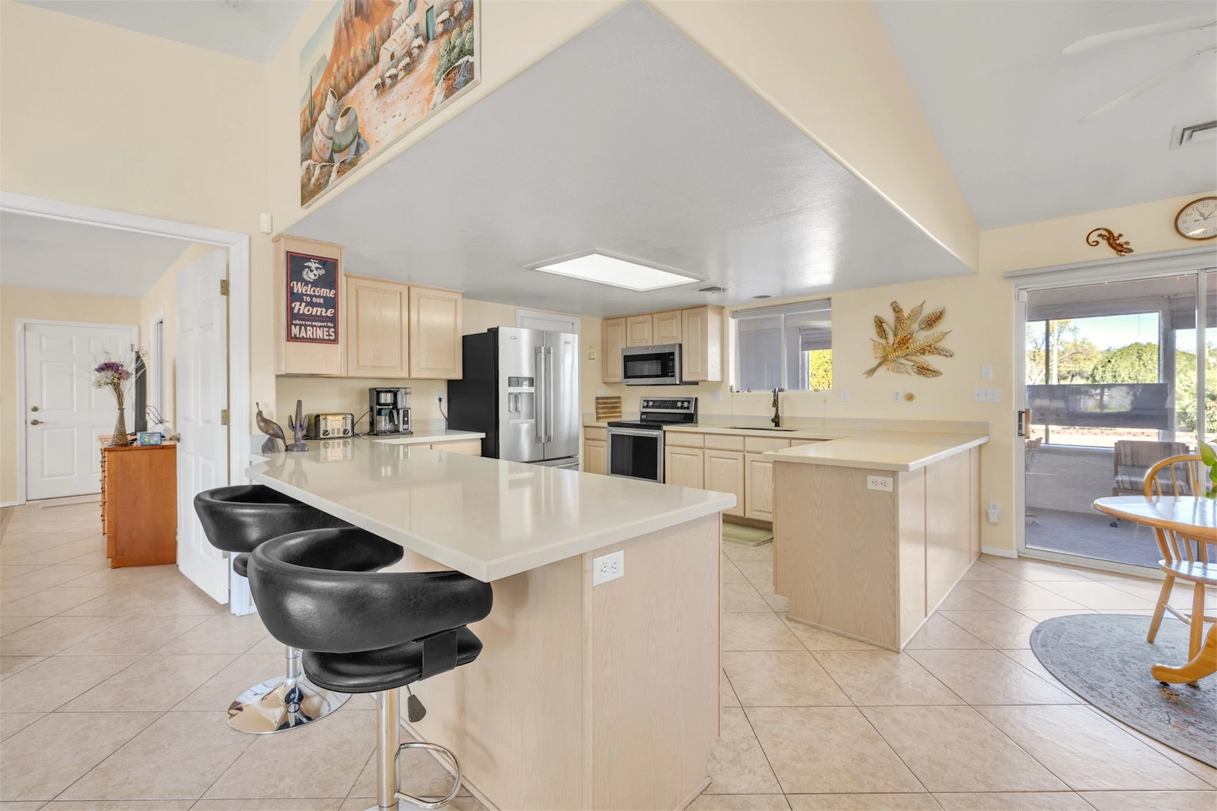 This modern kitchen interior in Queen Valley, AZ features light cabinetry, stainless steel appliances, and a spacious breakfast bar captured with professional real estate photography.