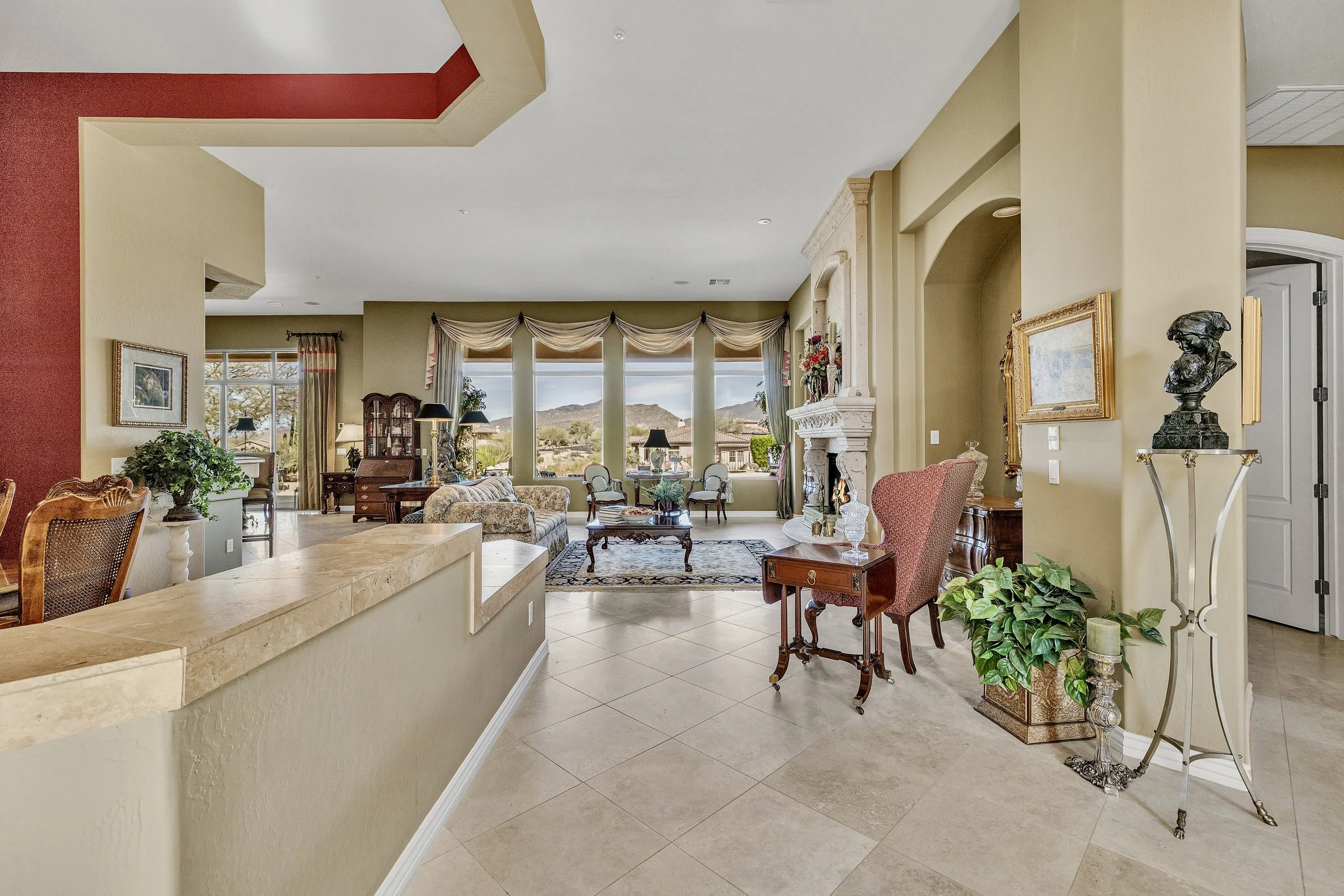 This Scottsdale, AZ living room features a cozy fireplace, large windows with mountain views, and classic furnishings, captured with expert real estate photography.