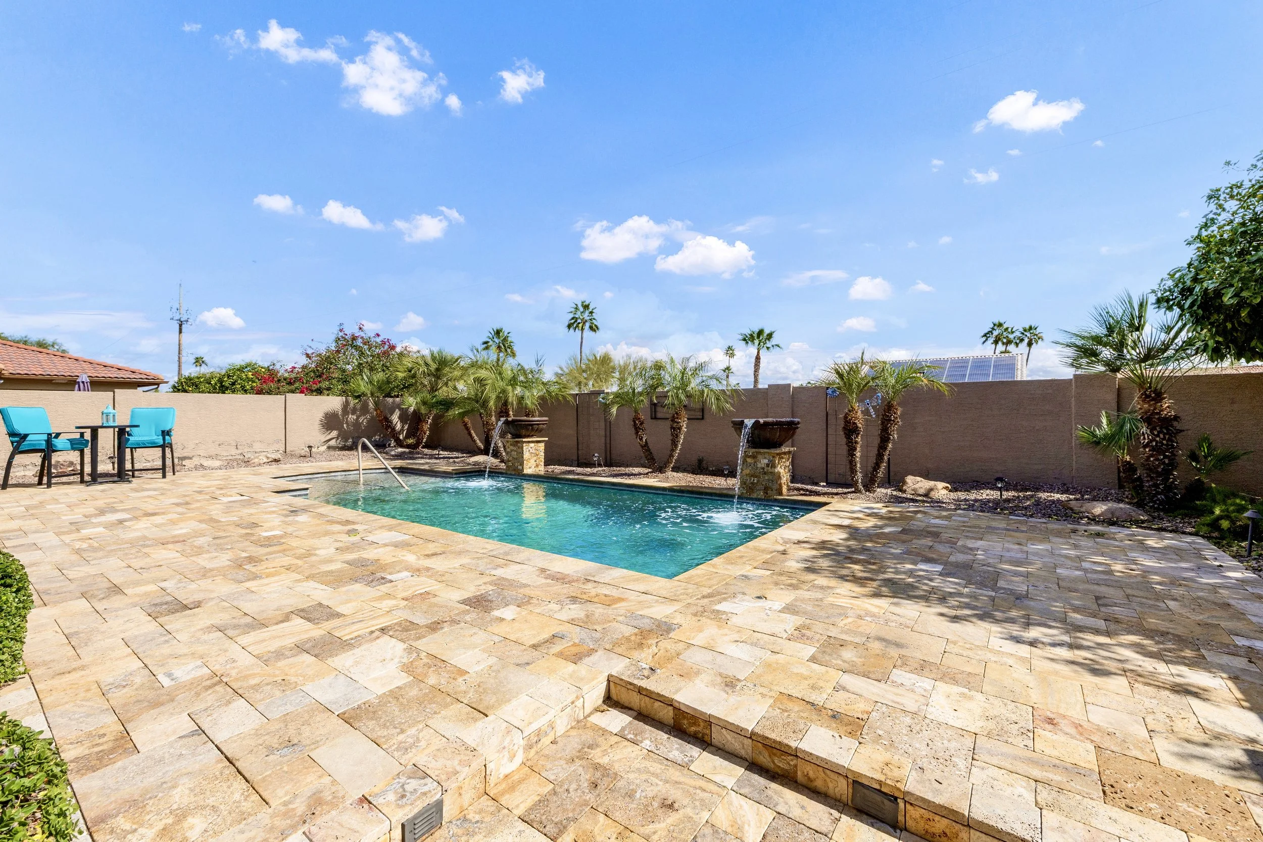 Beautiful backyard pool area with palm trees and stone patio in Sun Lakes, AZ, showcased with professional real estate photography.