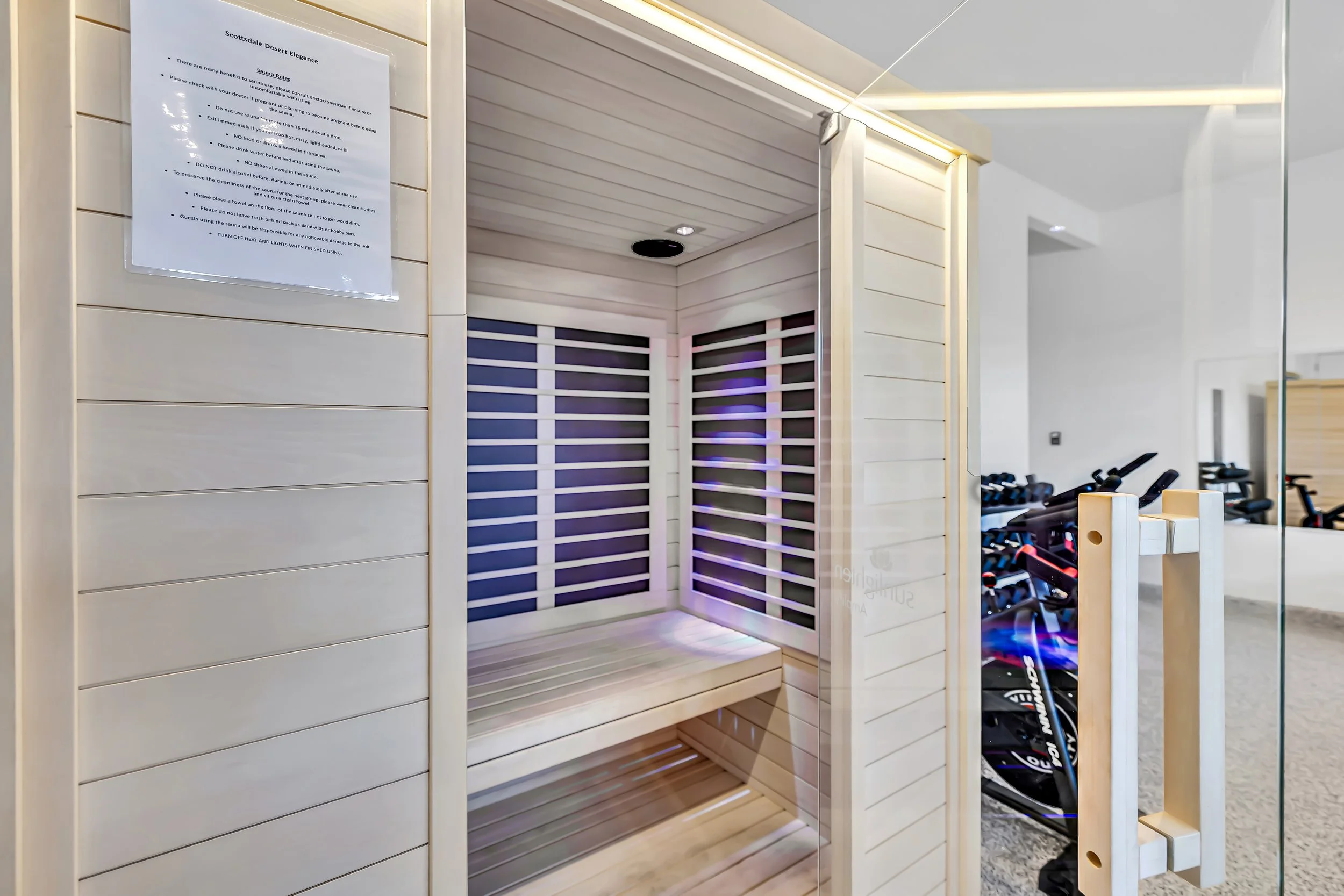 Modern indoor sauna with wood paneling and soft LED lighting inside a luxury home gym in Scottsdale, Arizona.
