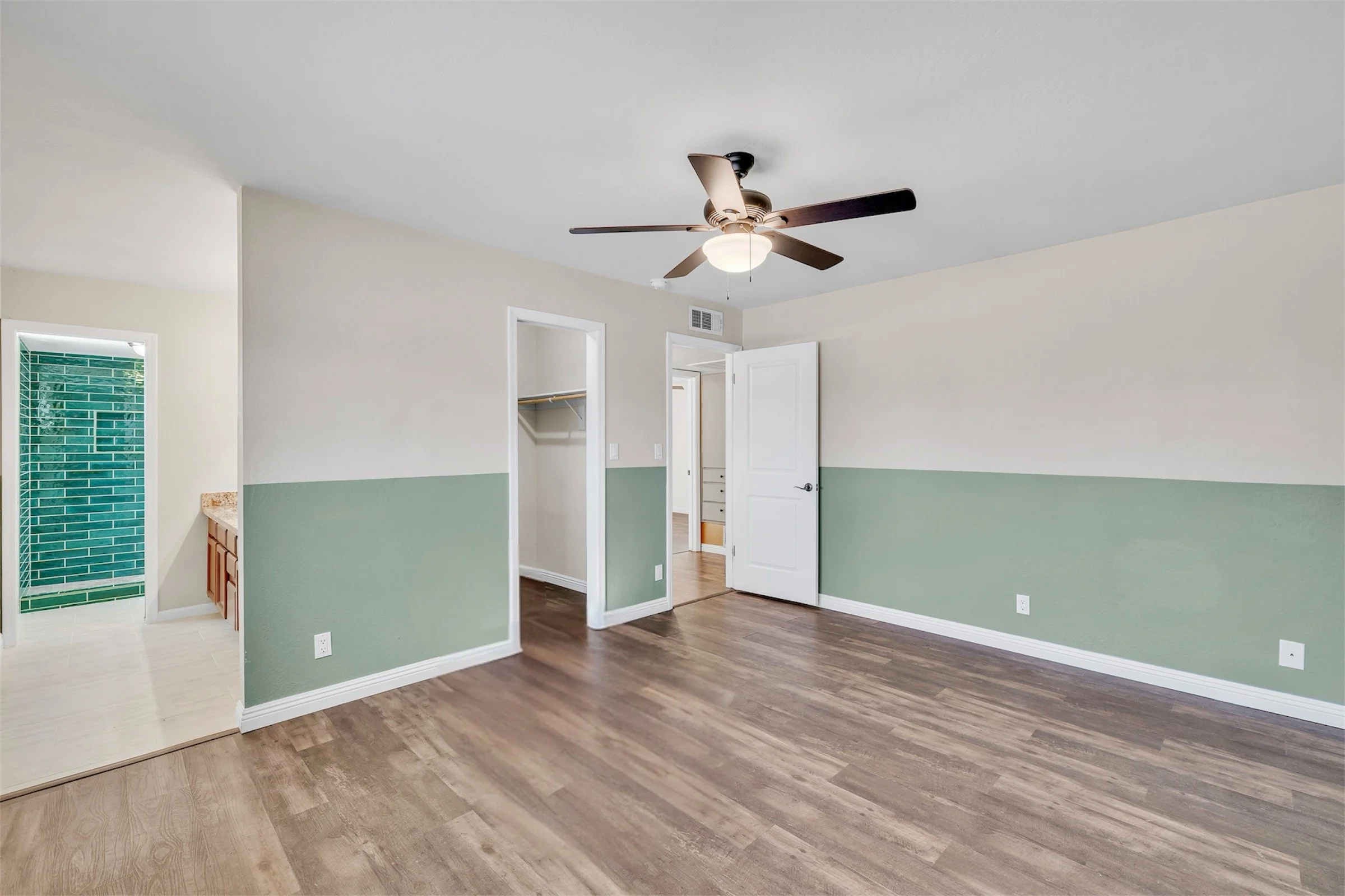 This Tempe, AZ bedroom features green accent walls and wood flooring, captured with professional real estate photography to highlight the home's inviting and modern interior space.