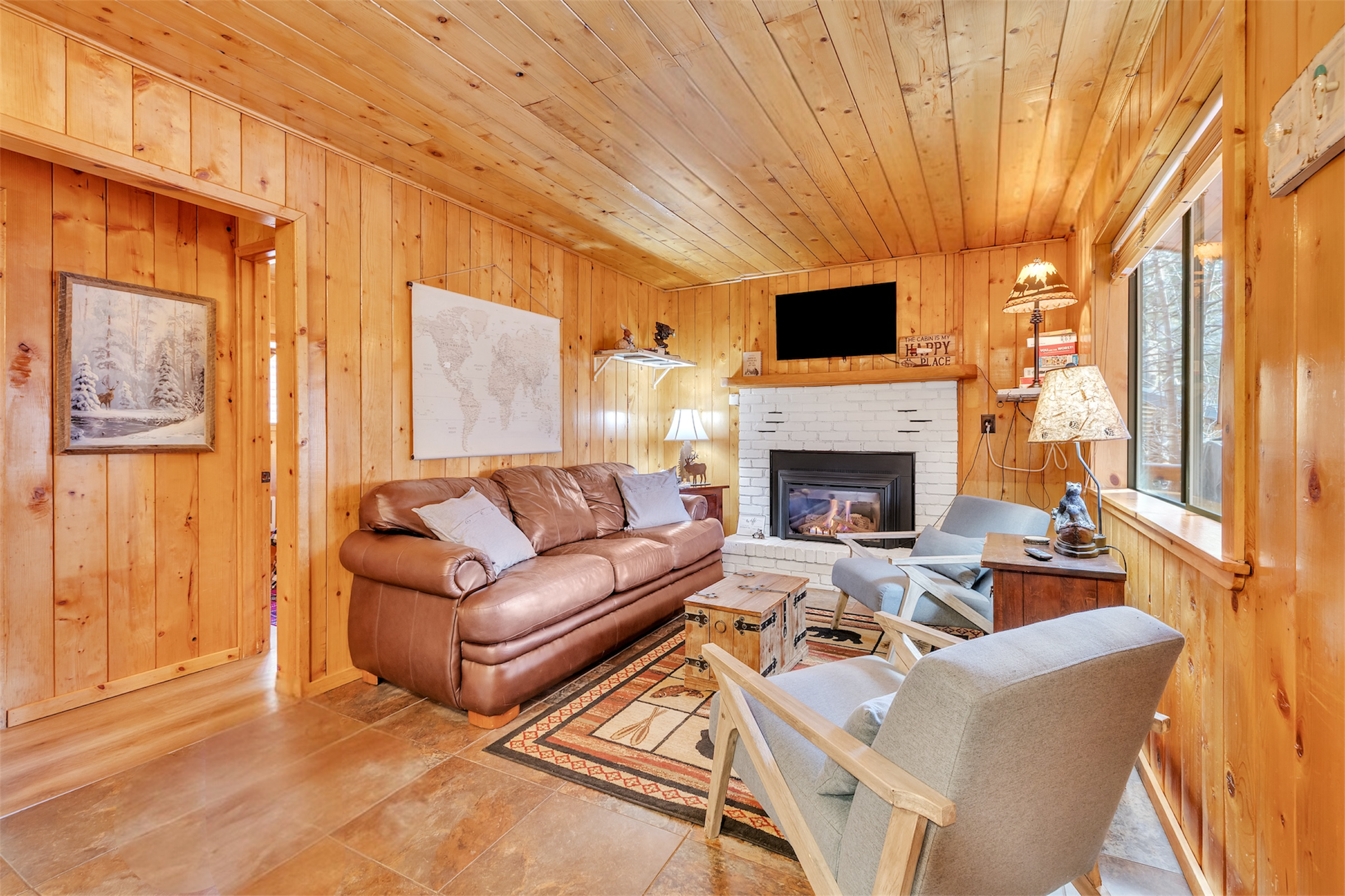 This cozy living room in Greer, AZ features wood-paneled walls, a fireplace, and comfortable seating, captured with expert real estate photography to showcase its inviting atmosphere.