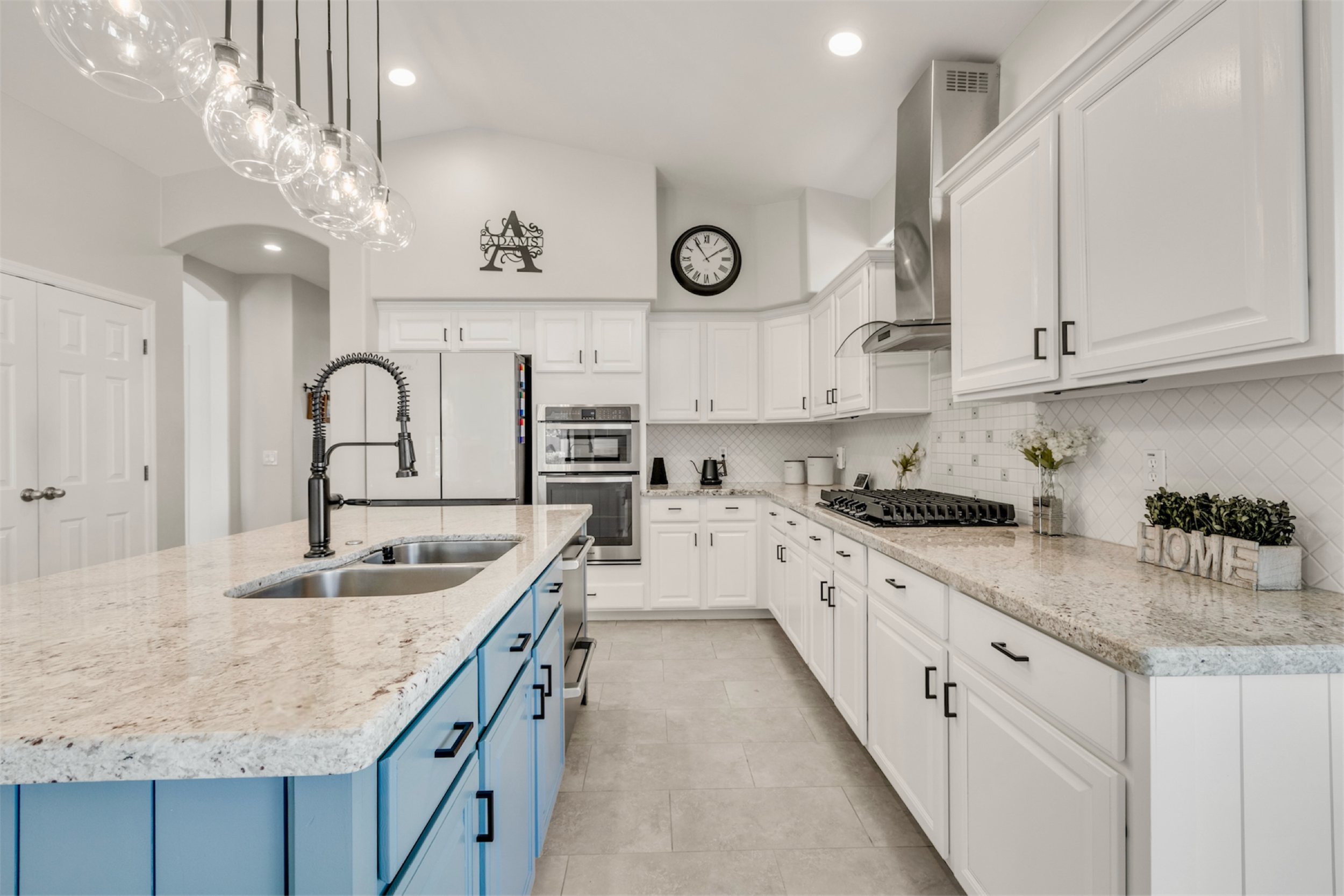 This bright and modern kitchen features a blue island and white cabinetry, highlighting clean design in a Gilbert, AZ home with professional real estate photography.