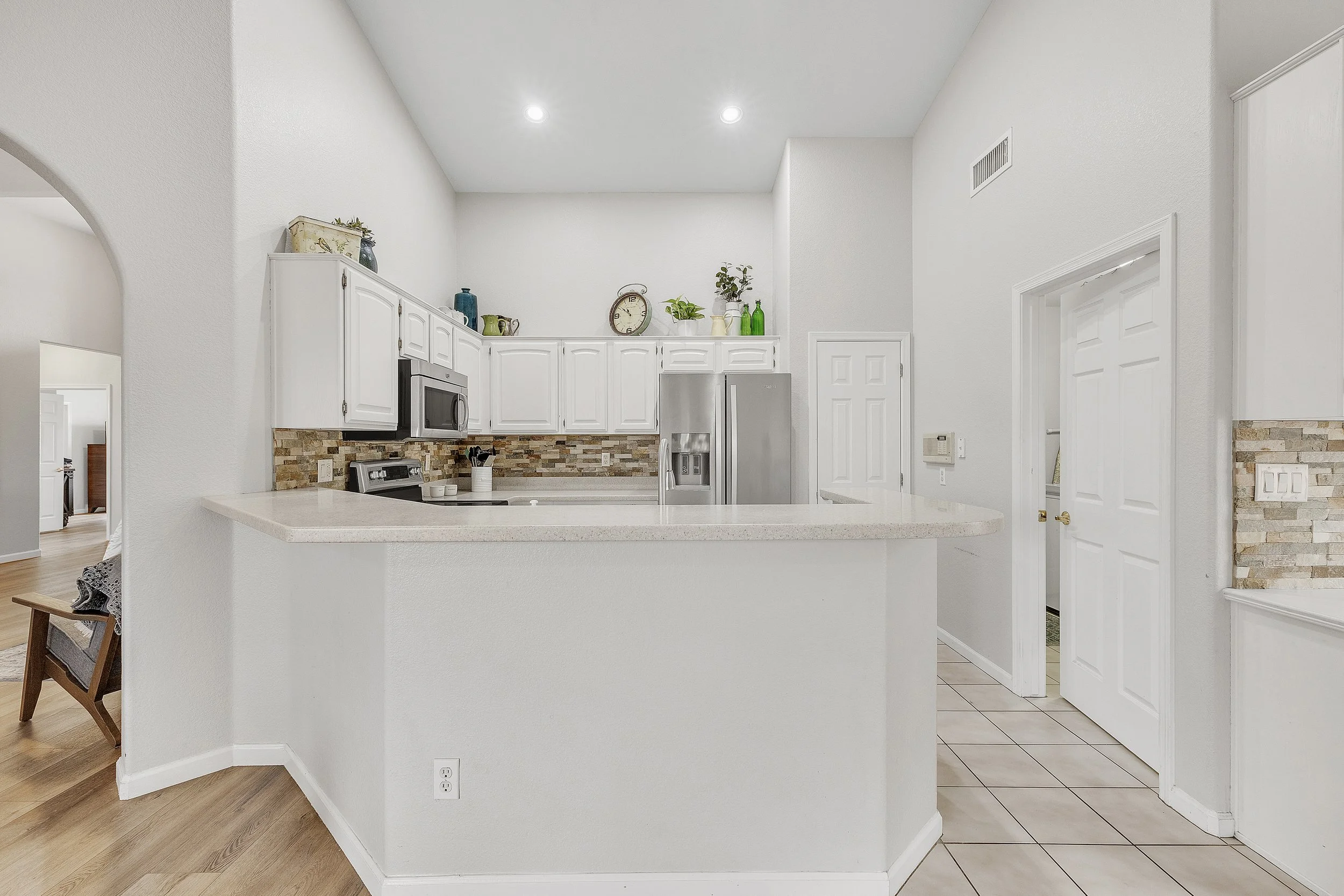 This bright kitchen in Goodyear, AZ features white cabinets, a bar counter, and modern appliances, captured with expert real estate photography to showcase its appeal.