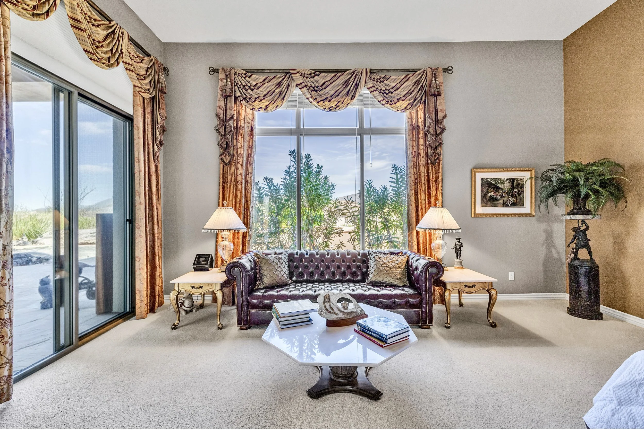 This elegant living room in Scottsdale, AZ features a leather sofa, large windows with luxurious curtains, and tasteful decor, captured with expert real estate photography to showcase its inviting atmosphere.