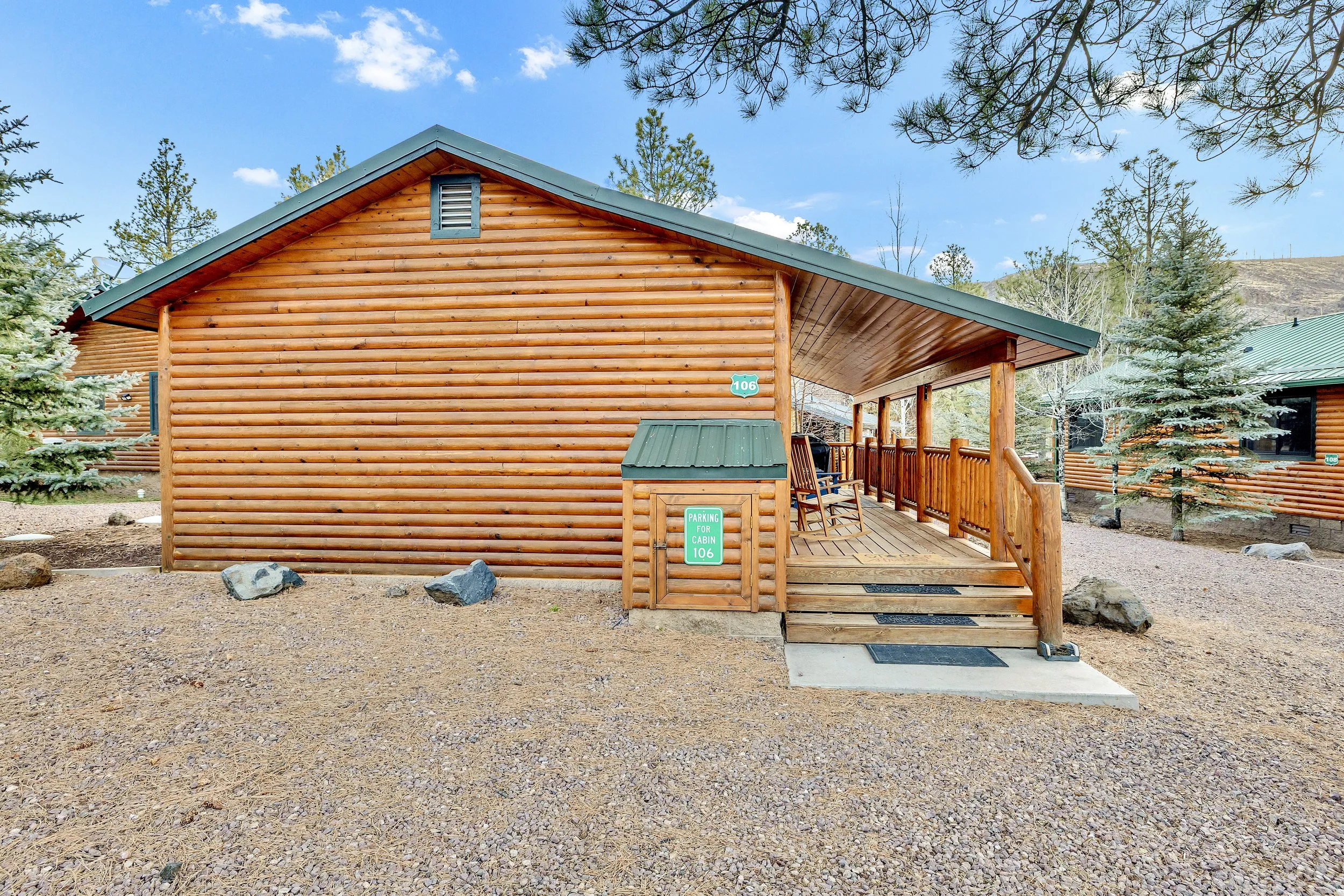 This log cabin exterior with covered porch and rocky yard is showcased in Greer, AZ, captured through professional real estate photography highlighting rustic charm and natural surroundings.