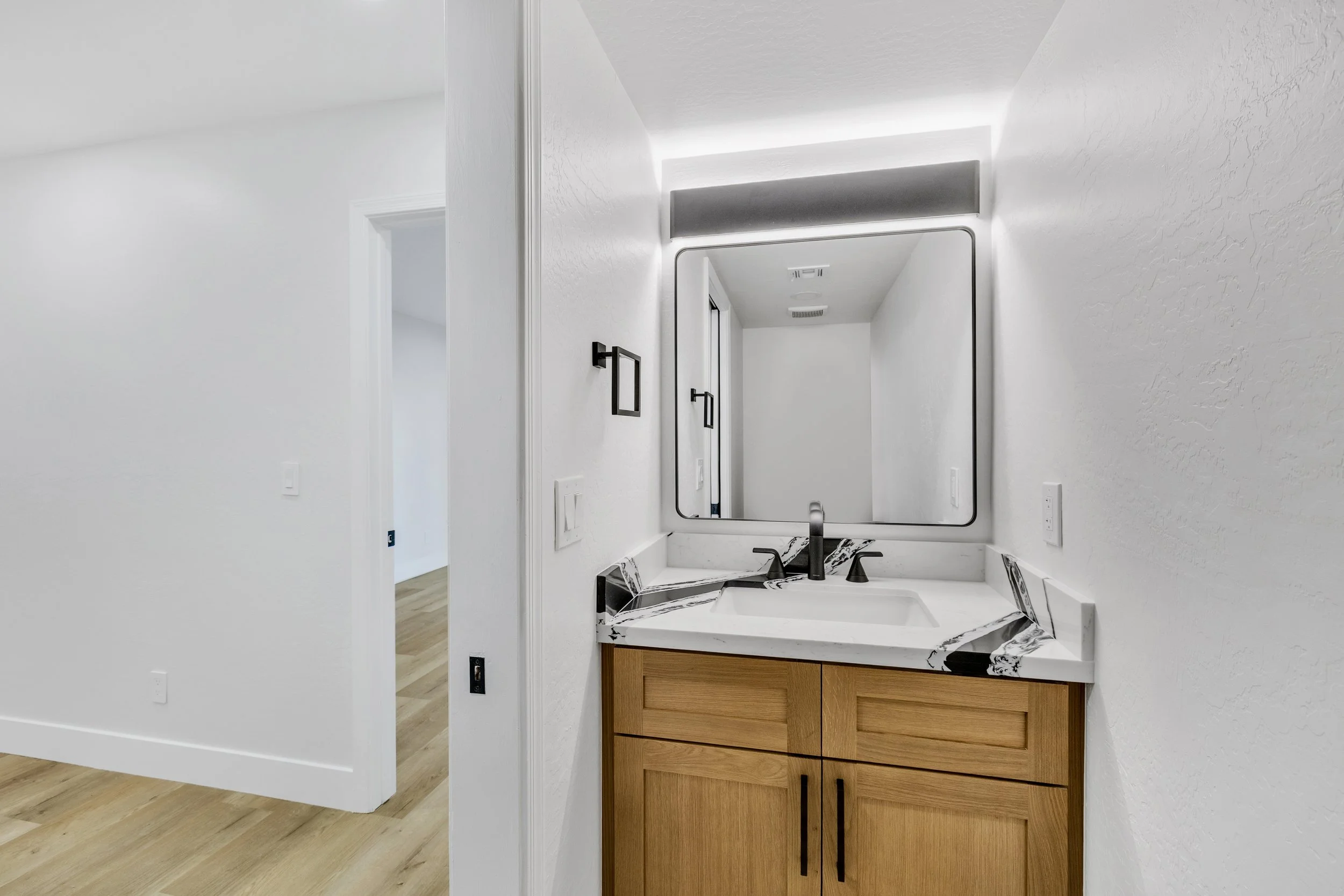 This modern bathroom vanity with wood cabinets and marble countertop showcases elegant design captured through expert real estate photography in Chandler, AZ.