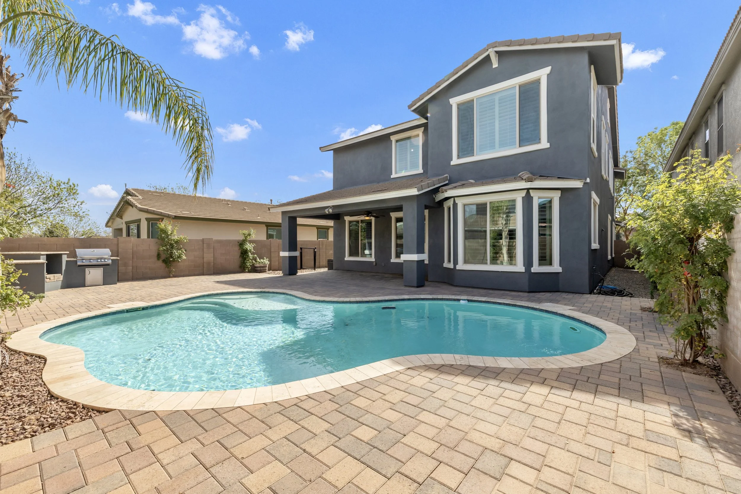 Beautiful backyard with a swimming pool and patio area captured in real estate photography in Gilbert, AZ in Morrison Ranch neighborhood.