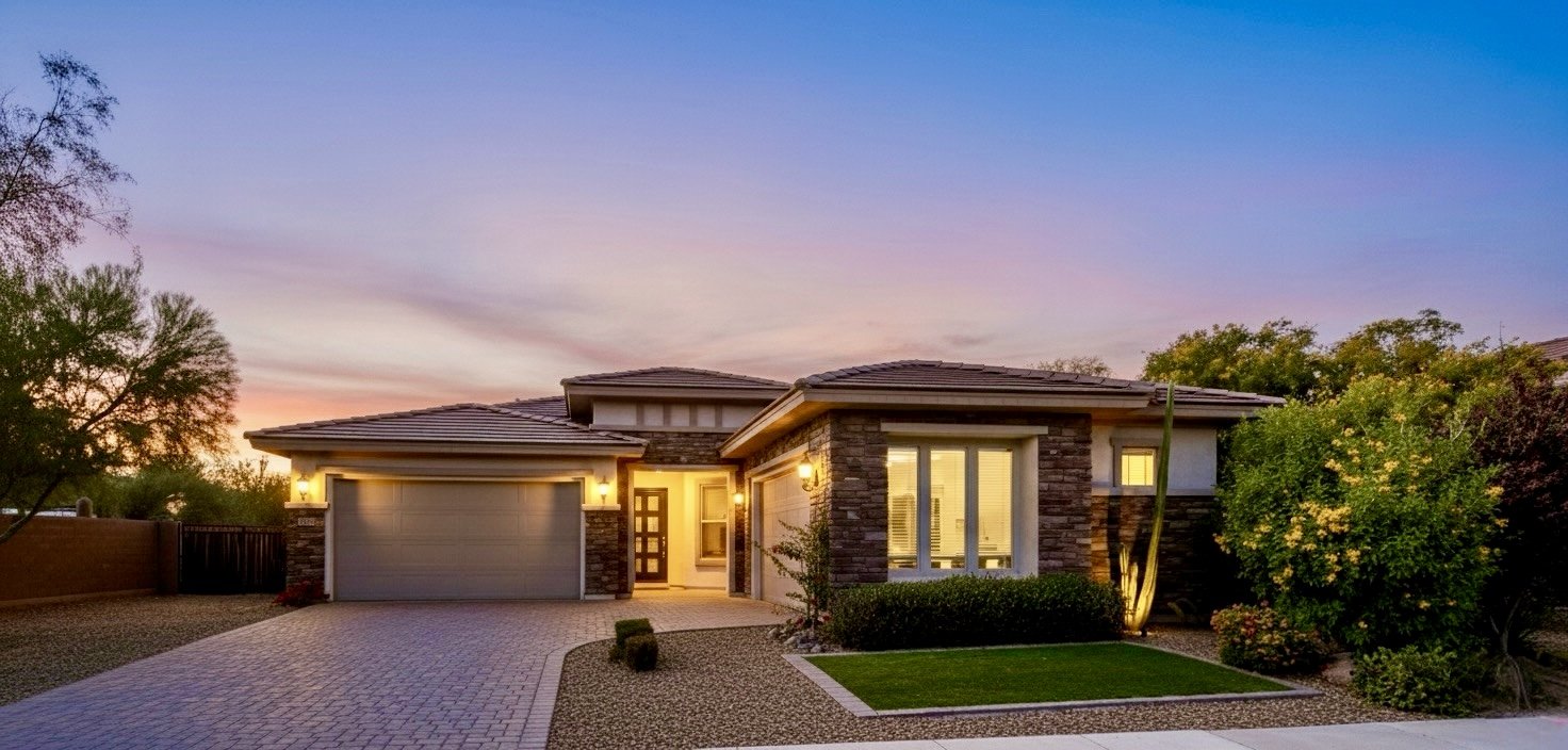 Beautiful twilight exterior of a modern home in Phoenix, AZ, showcasing professional real estate photography with warm lighting and well-maintained landscaping.