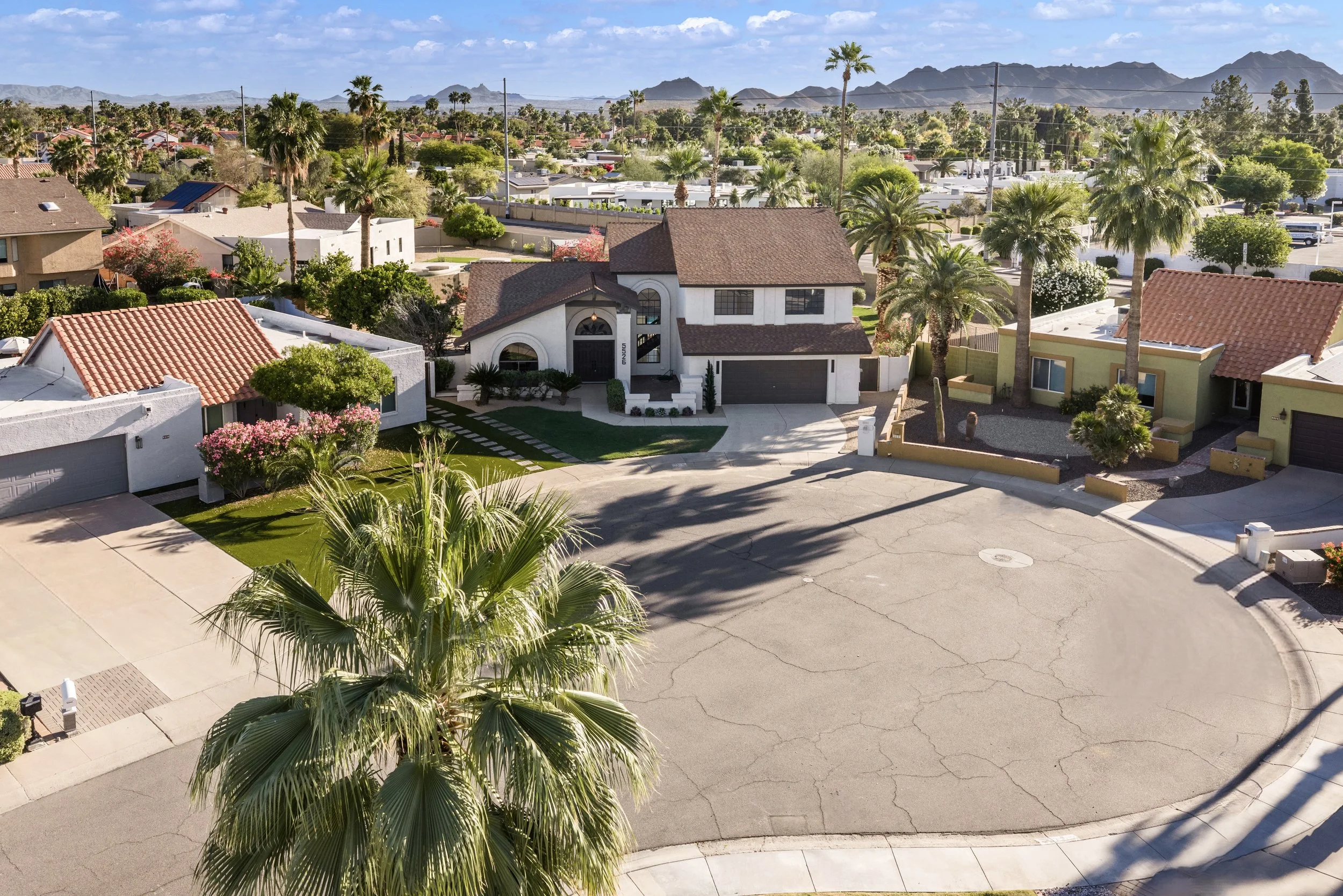 Aerial real estate photography showcases beautiful homes in a sunny Scottsdale, AZ neighborhood with mountain views and palm trees, perfect for prospective buyers.