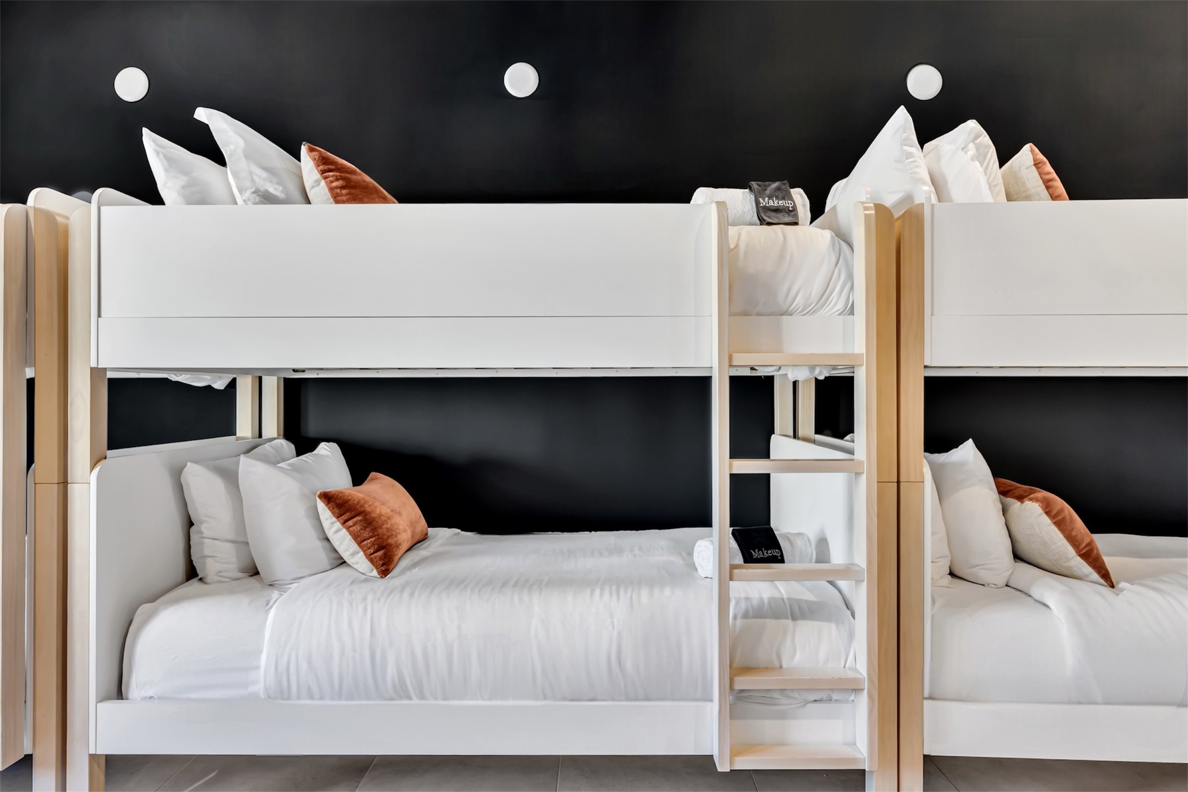 Modern bunk room with matte black walls, built-in white bunk beds, warm-toned pillows, and soft natural light in Scottsdale, Arizona.