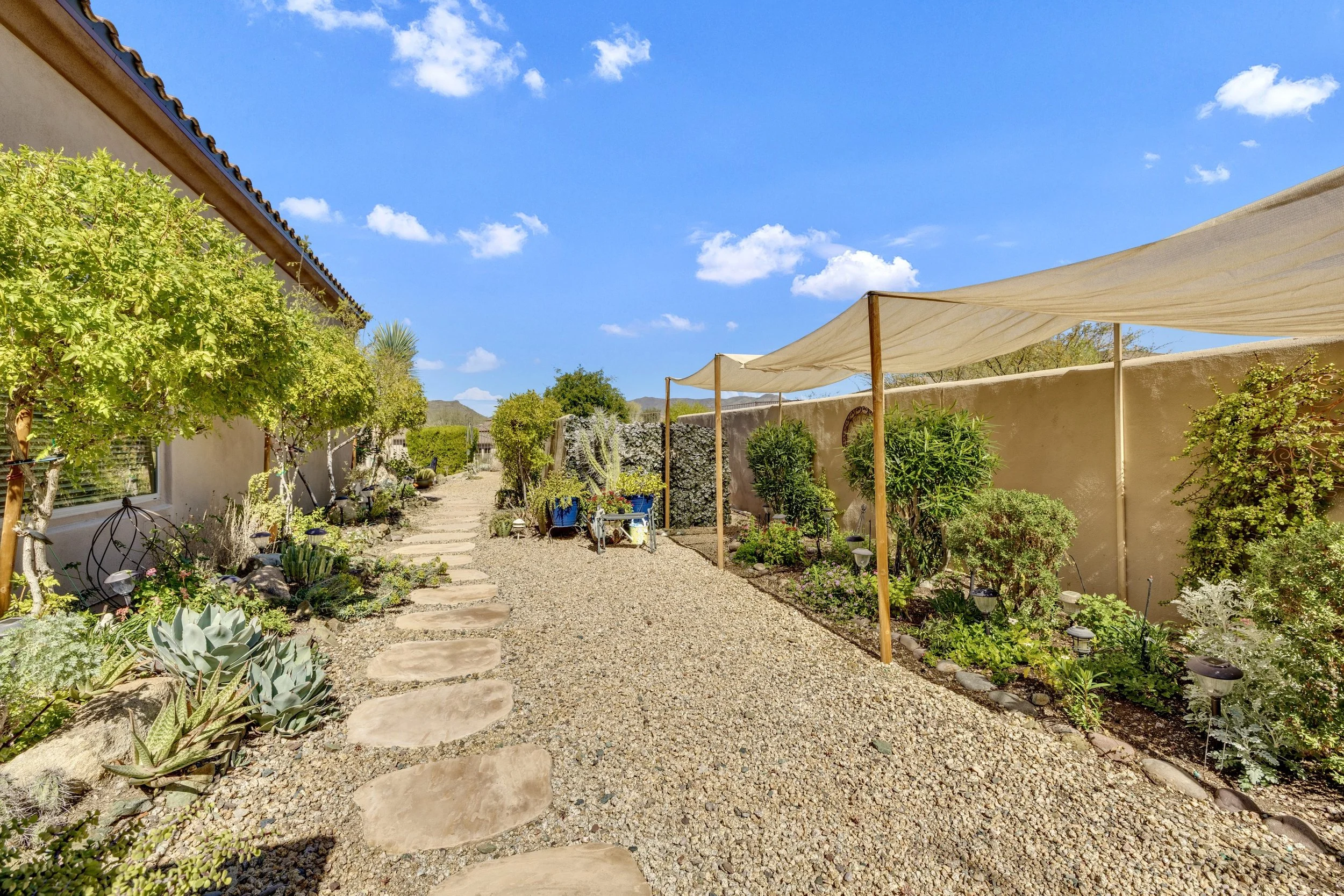This beautifully landscaped backyard in Scottsdale, AZ features a shaded desert garden pathway with lush greenery, captured with expert real estate photography to showcase outdoor living.