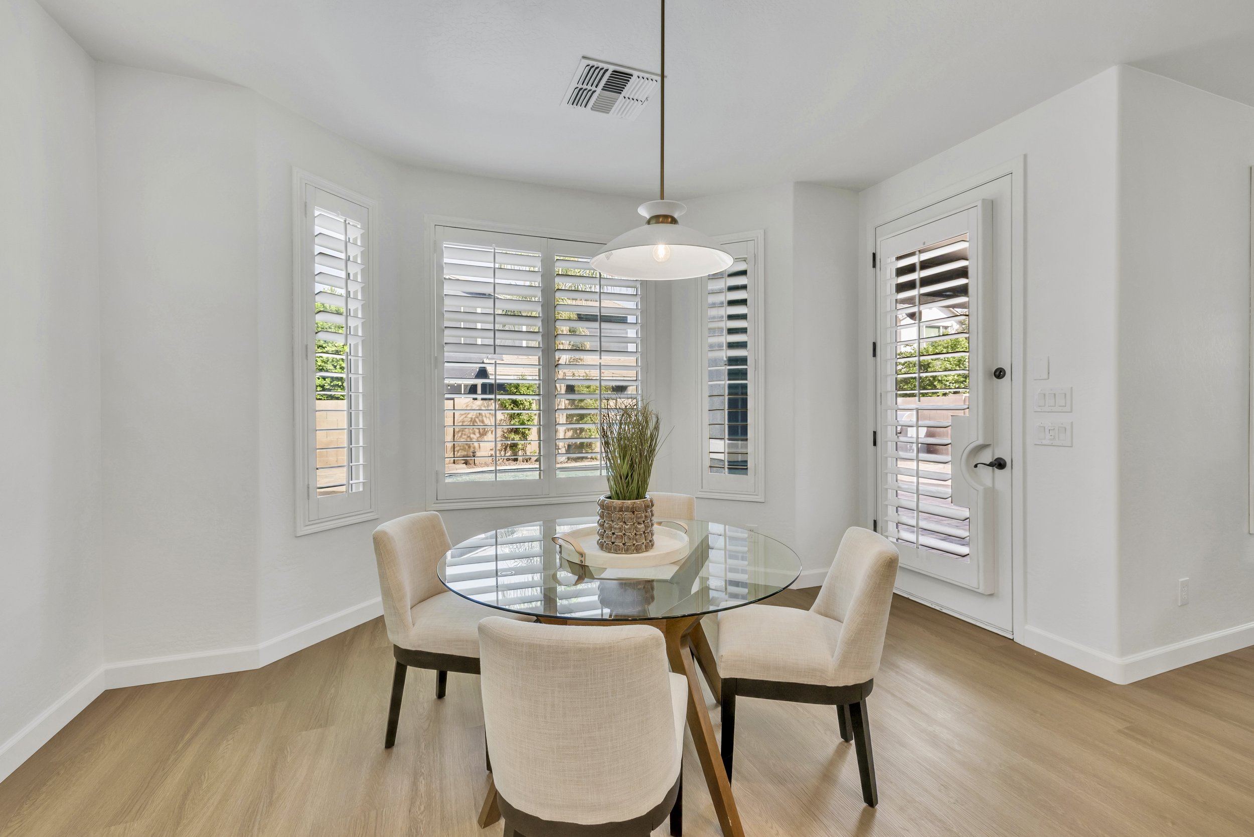 Bright dining room with a glass table and modern pendant light captured in real estate photography in Morrison Ranch neighborhood, Gilbert, AZ.