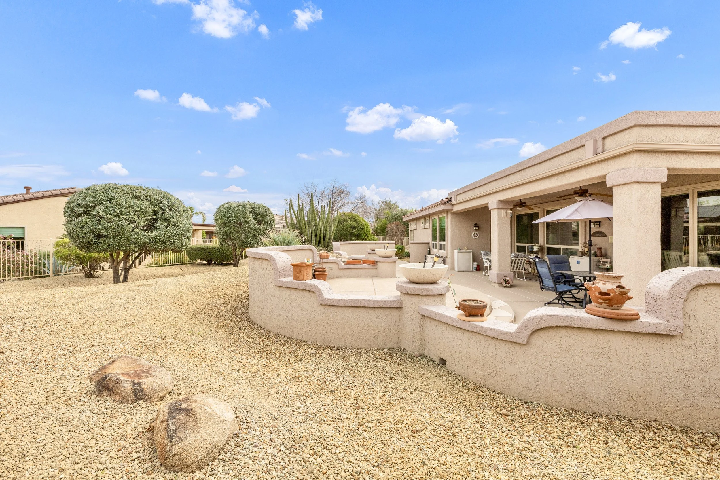This spacious backyard patio with desert landscaping is captured in beautiful real estate photography in Surprise, AZ, highlighting a relaxing outdoor area perfect for entertaining or enjoying the warm weather.