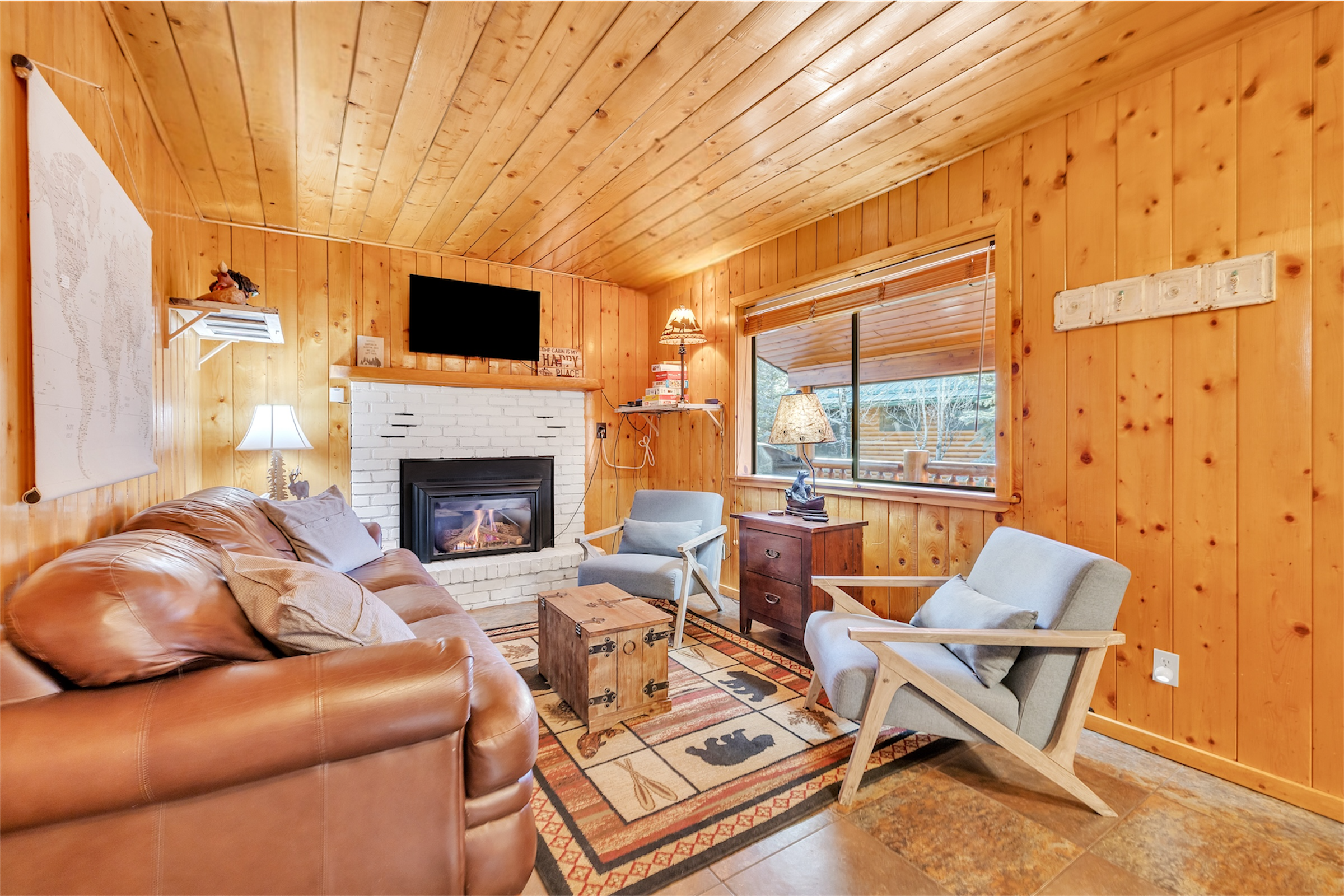 This cozy living room in Greer, AZ features wood-paneled walls, a brick fireplace, and comfortable seating, captured perfectly with expert real estate photography.