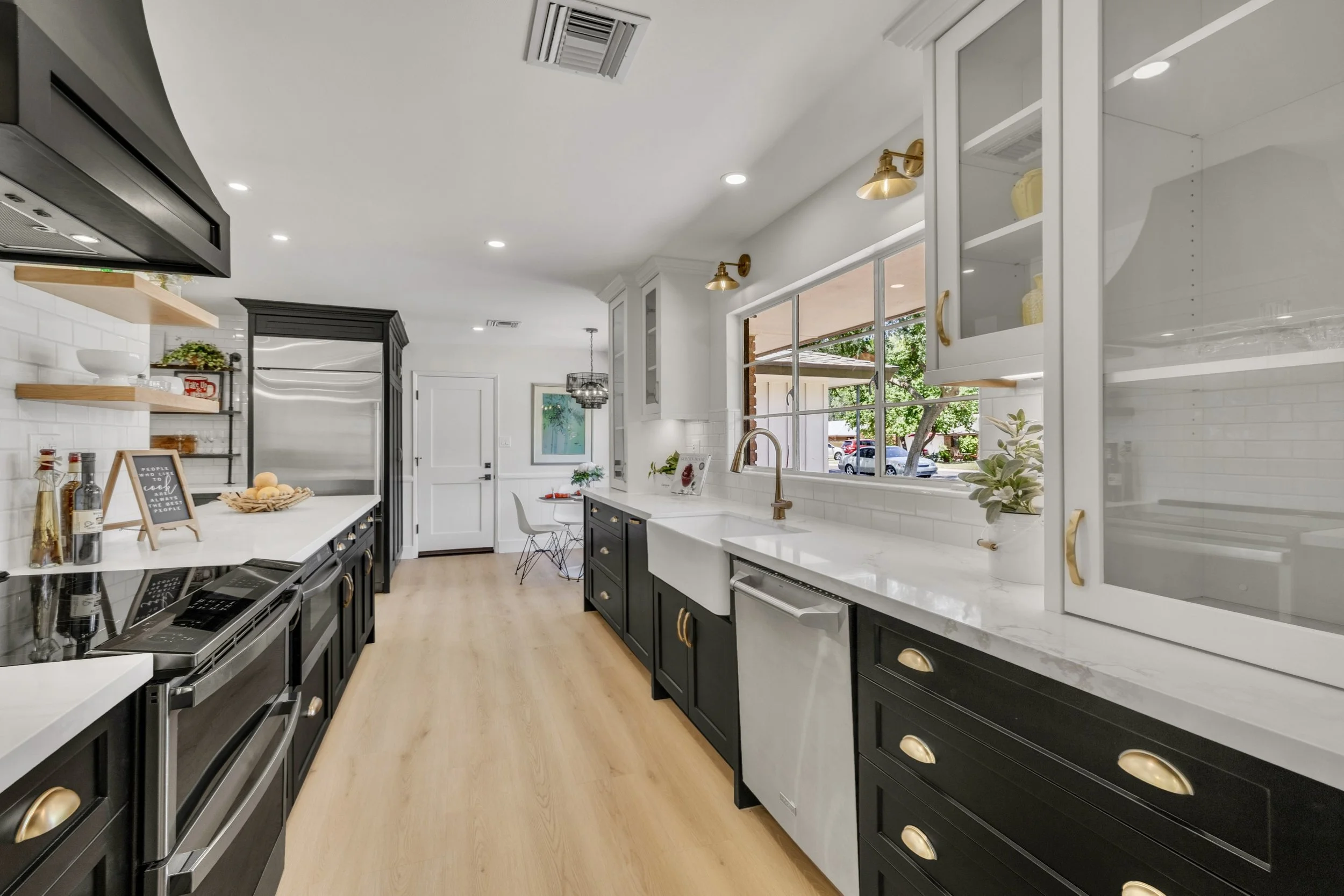 This modern kitchen in Phoenix, AZ features black cabinetry, stainless steel appliances, and bright natural lighting, professionally captured with expert real estate photography to showcase its stylish design.