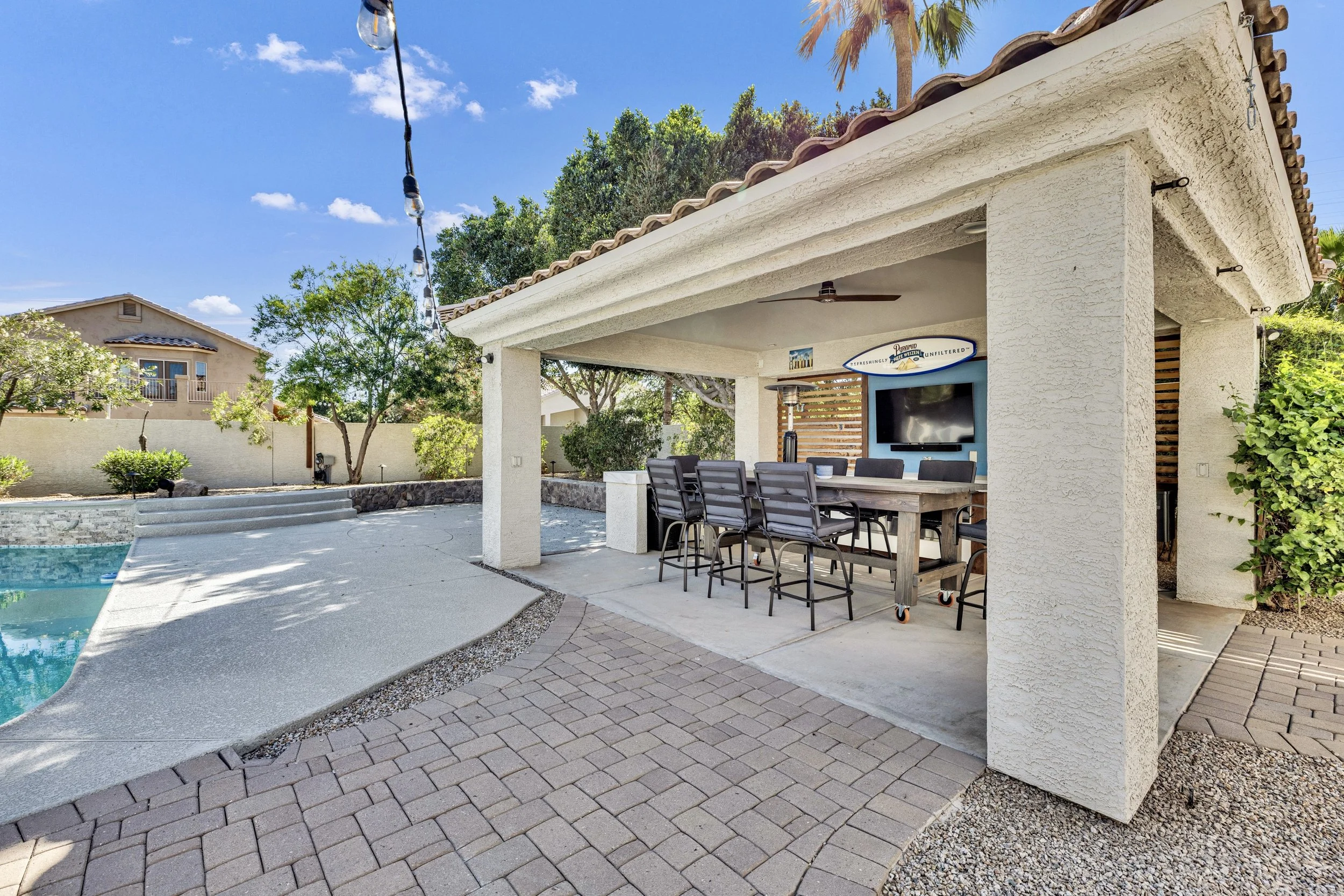 This Gilbert, AZ home features a covered patio with outdoor dining and a pool, captured with professional real estate photography to highlight its inviting backyard space.