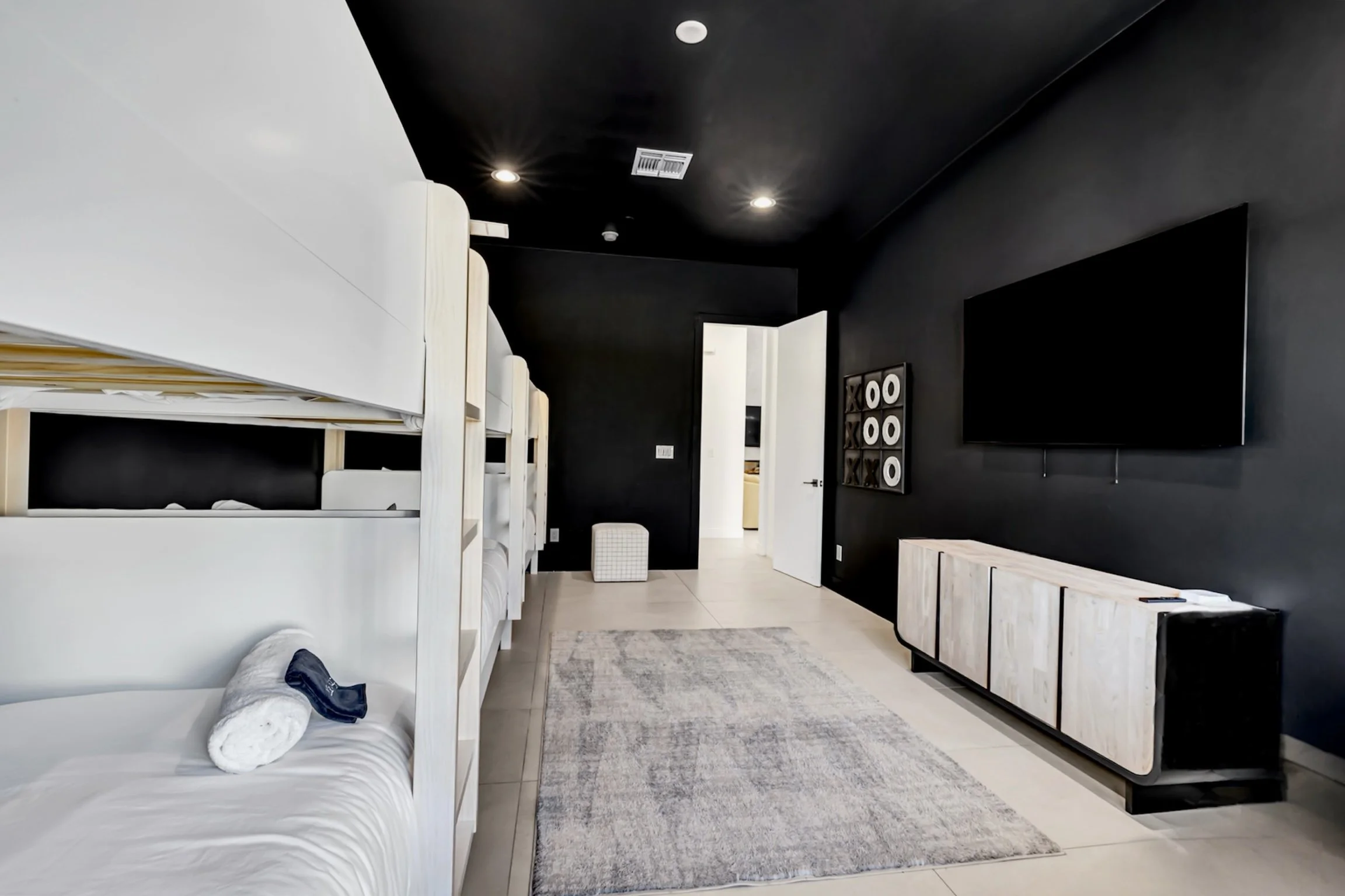 Contemporary bunk room featuring multiple bunk beds, a wall-mounted TV, minimalist cabinetry, and a cozy gray rug in Scottsdale, Arizona.
