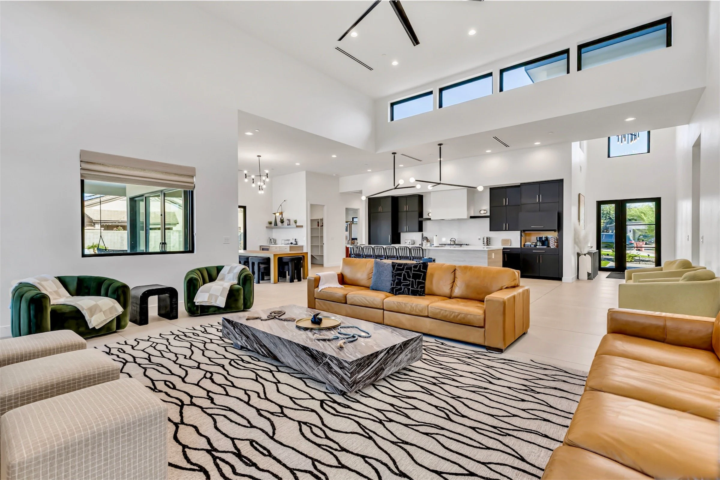 Open-concept living room facing the kitchen, featuring tan sofas, modern light fixtures, and high clerestory windows in Scottsdale, Arizona.