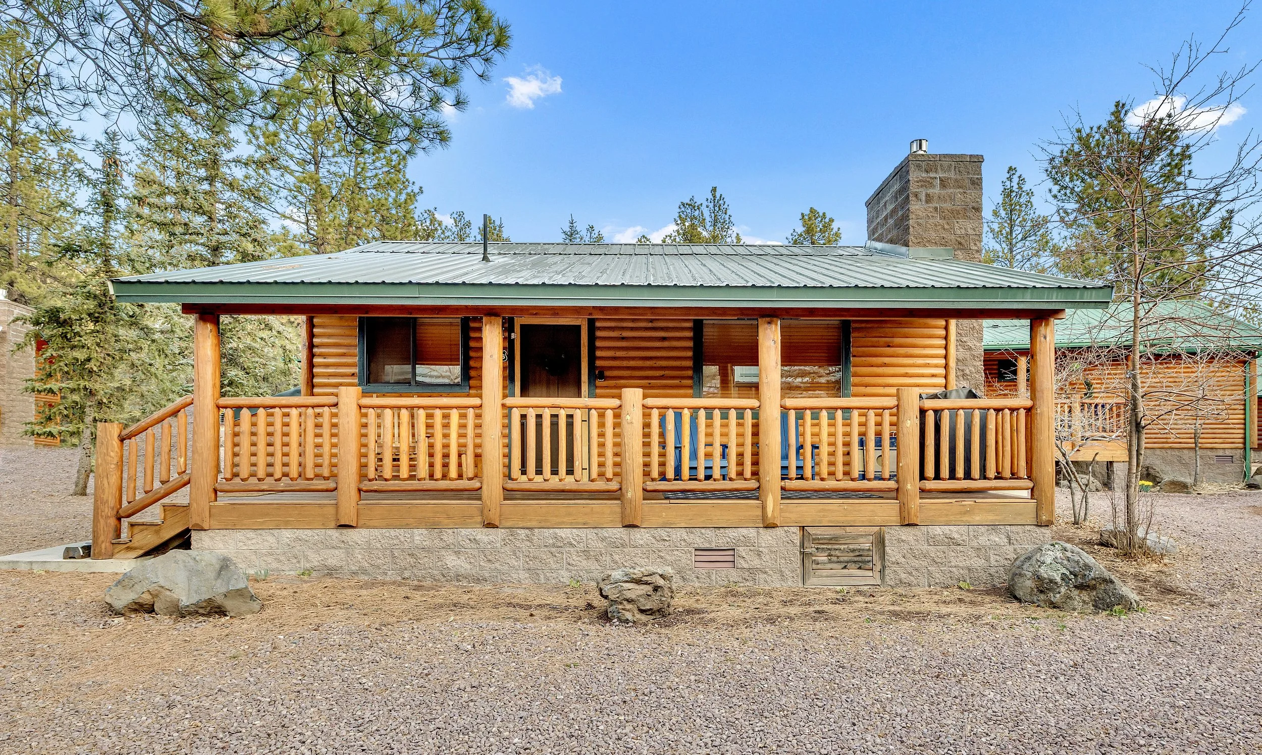 This log cabin exterior features a charming porch surrounded by forested land, offering a rustic home opportunity in Greer, AZ, captured with expert real estate photography.