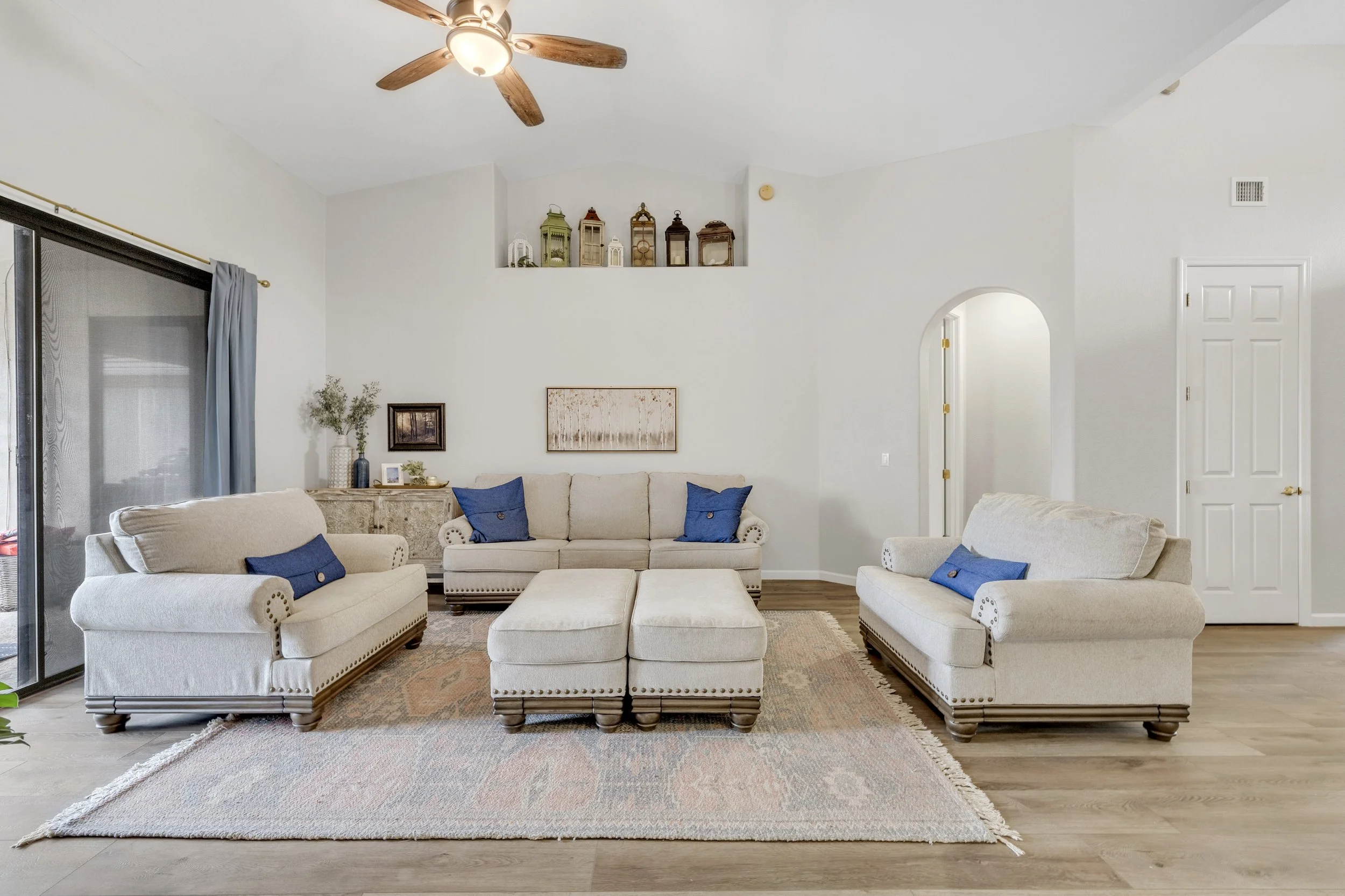 Bright and airy living room in Goodyear, AZ featuring plush sofas, a ceiling fan, and tasteful decor captured with expert real estate photography.