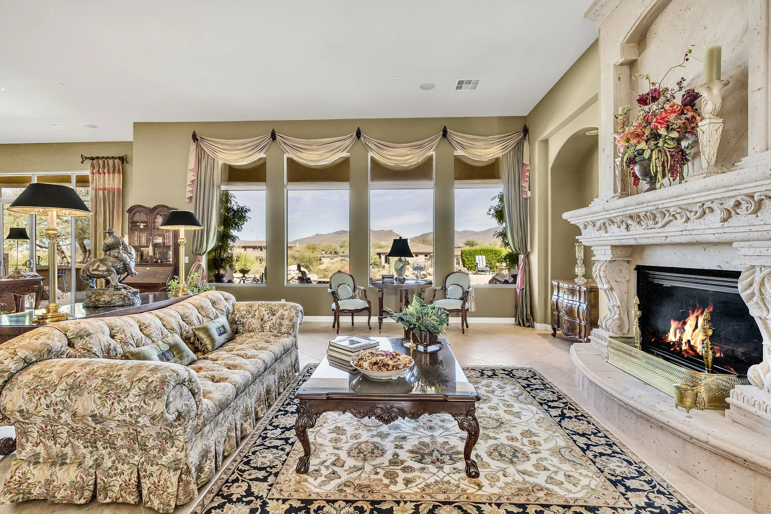 This Scottsdale, AZ living room features a grand fireplace, large windows with scenic views, and elegant furnishings captured with premium real estate photography.