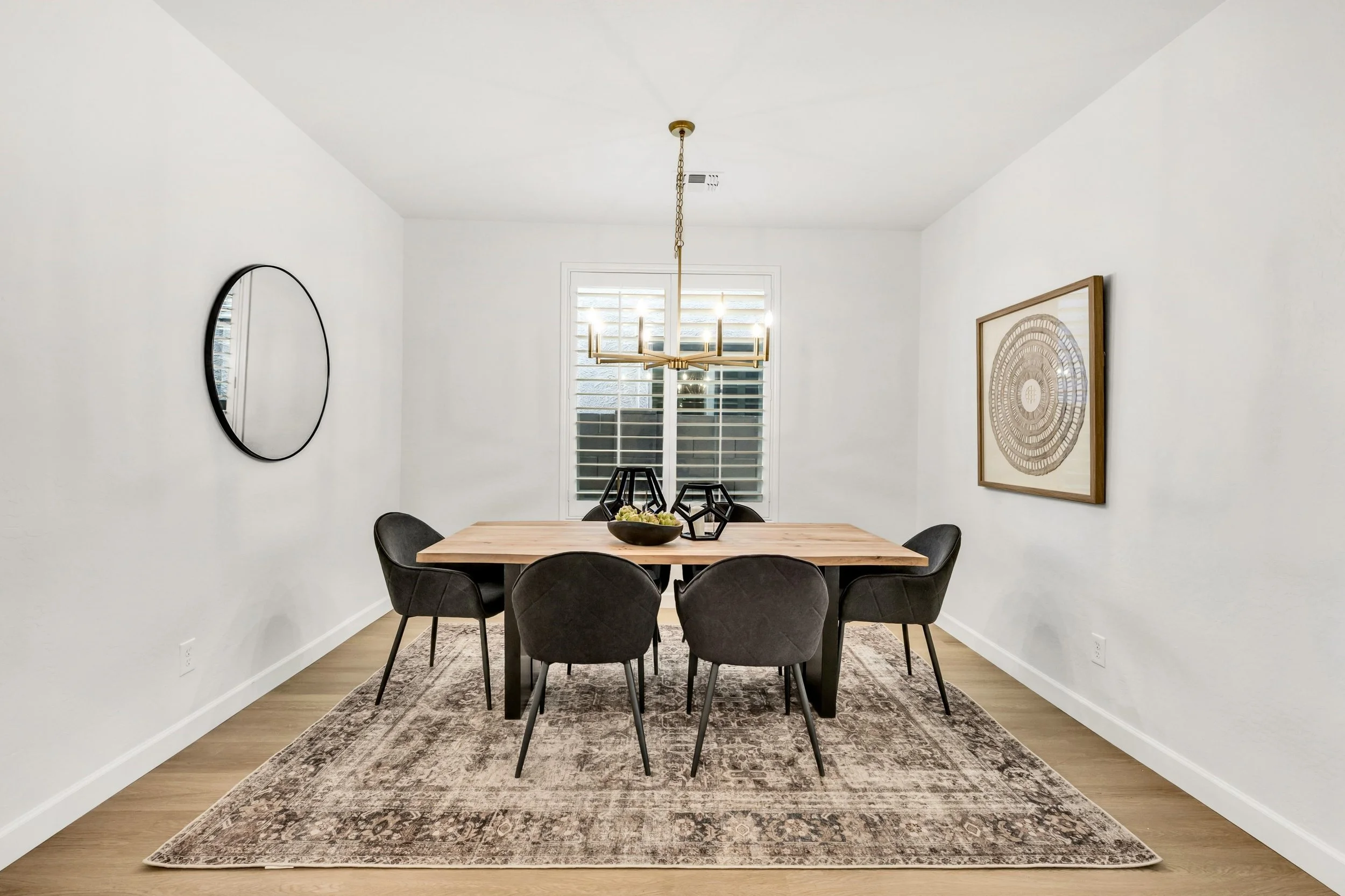 This minimalist dining room features a modern chandelier and decorative accents, ideal for stylish living in Gilbert, AZ real estate photography.