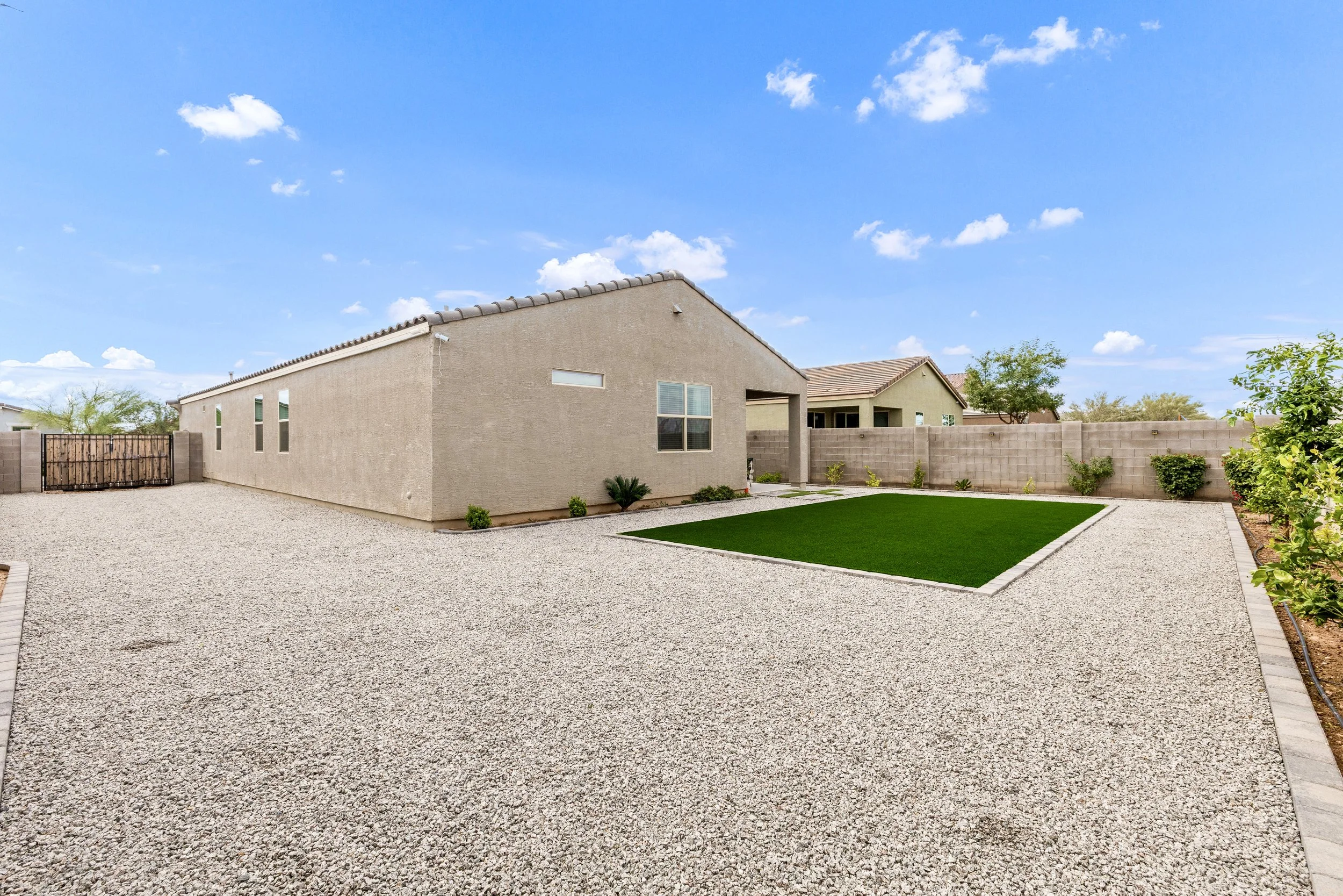 This exterior backyard features a spacious gravel area and a small lush lawn, perfect for outdoor activities in San Tan Valley, AZ, captured with expert real estate photography.