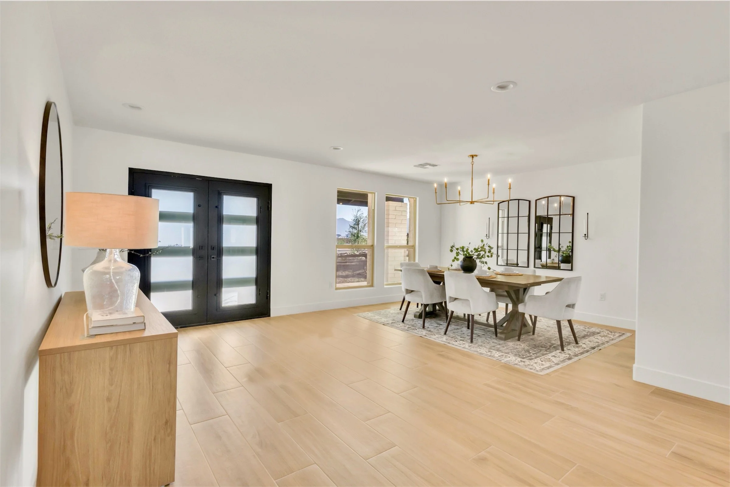 Open concept entryway and dining area with modern chandelier and double front doors in Phoenix, AZ.
