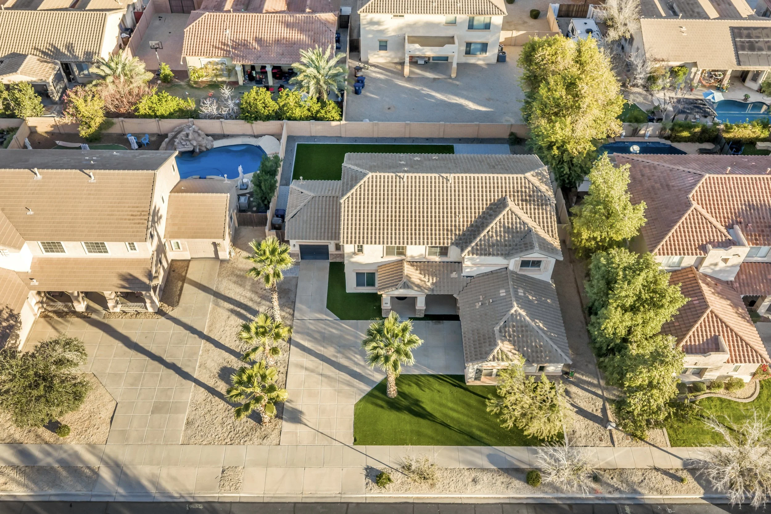 Top-down drone shot of an Arizona residential property showing tile roof, backyard layout, and surrounding homes.
