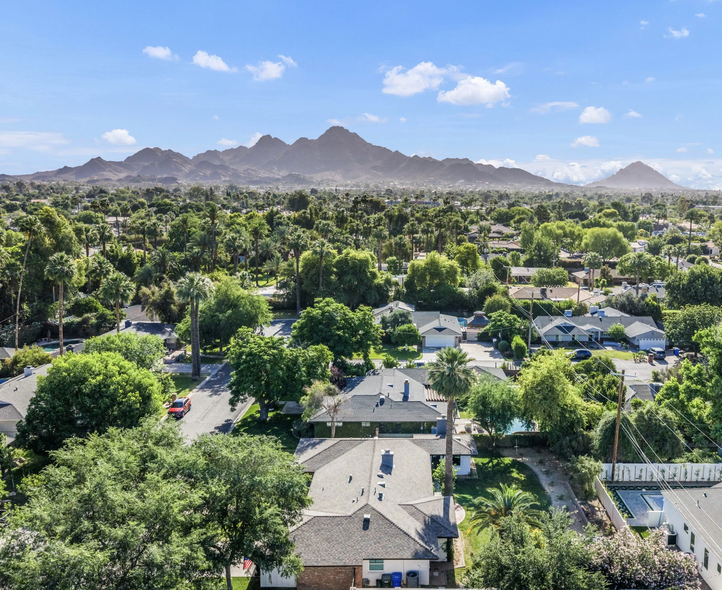 Stunning aerial real estate photography capturing a lush residential neighborhood with abundant greenery and mountain views in Phoenix, AZ.