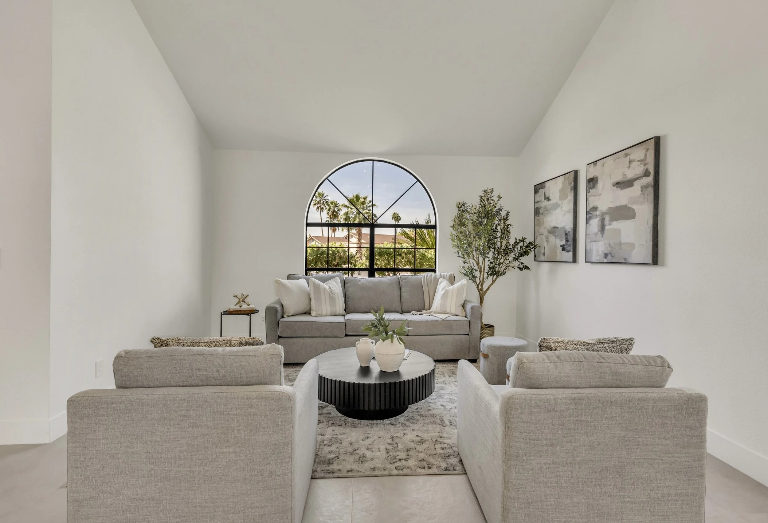 This modern living room with an arched window offers bright and elegant space, showcased through expert real estate photography in Scottsdale, AZ.