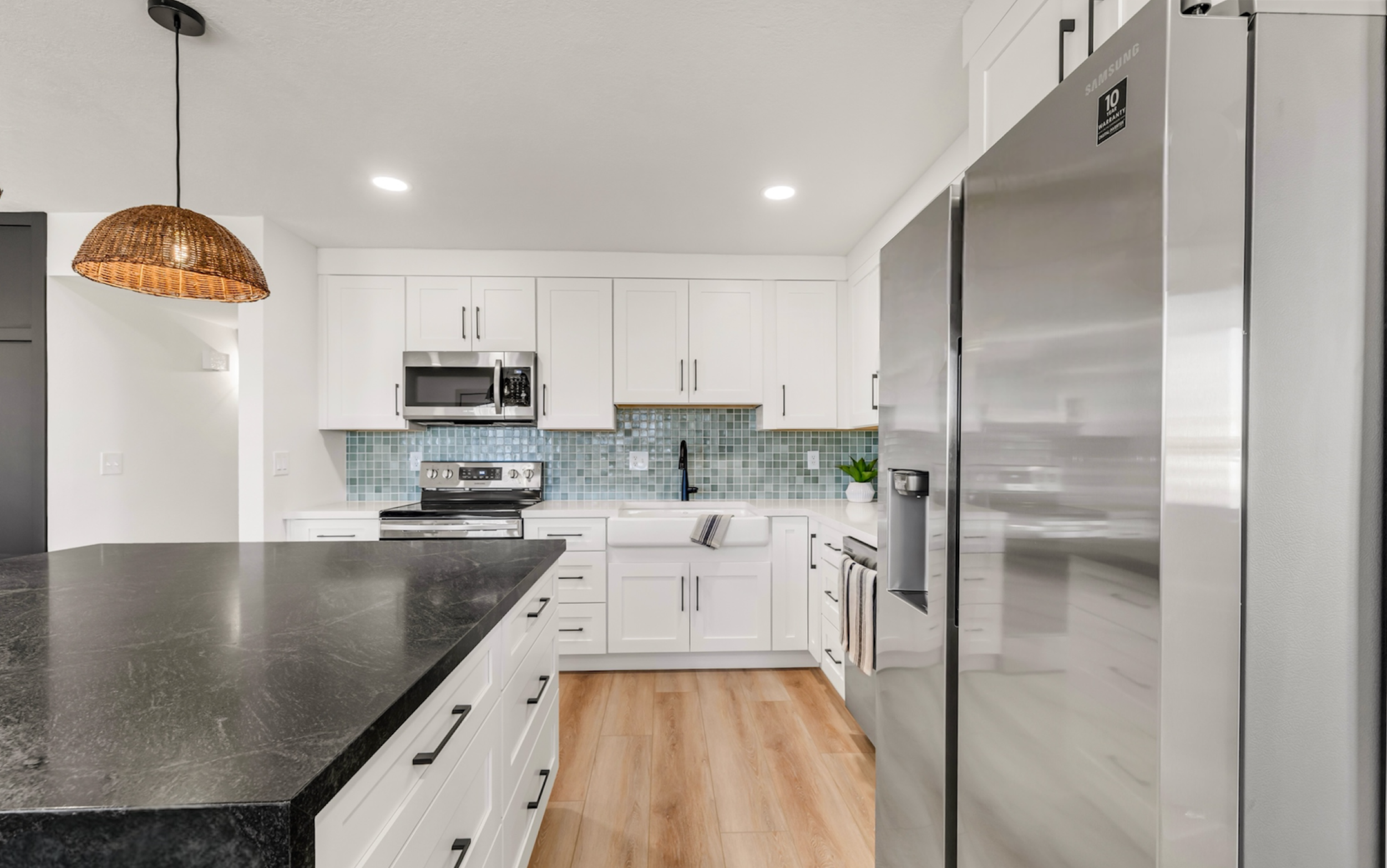 This modern kitchen in Mesa, AZ features stainless steel appliances, white cabinetry, and a stylish blue tile backsplash, captured with professional real estate photography.
