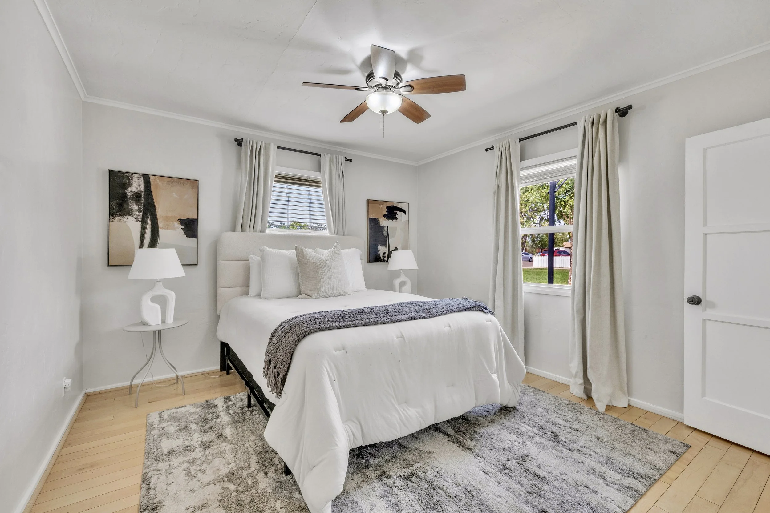 This bedroom in Phoenix, AZ features natural light, neutral decor, and cozy bedding, captured with professional real estate photography to highlight its inviting atmosphere.