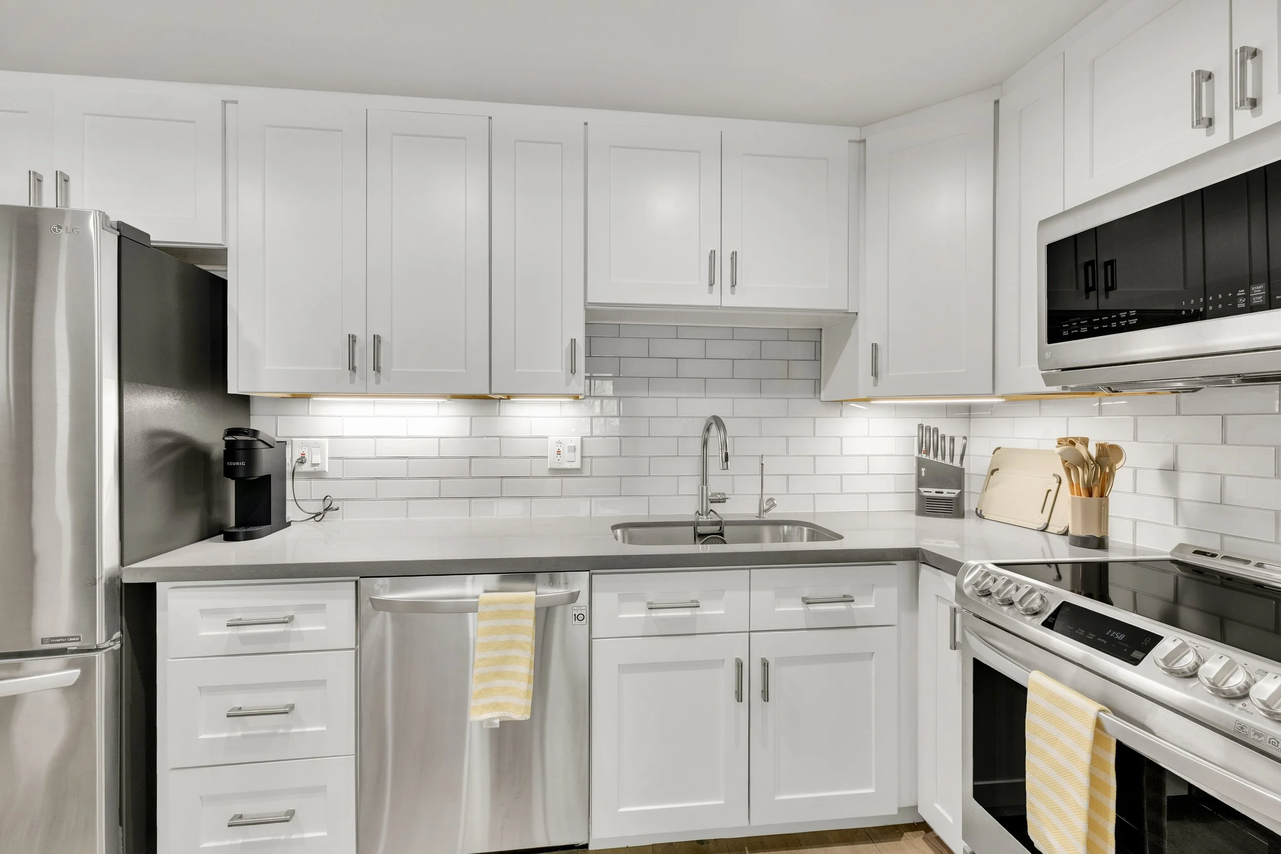 This modern white kitchen features stainless steel appliances and a bright tiled backsplash, showcased in professional real estate photography in Paradise Valley, AZ.