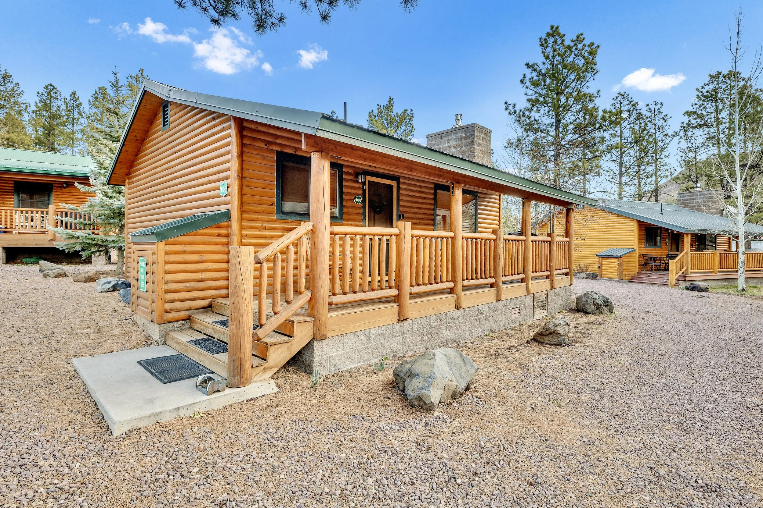 This charming log cabin in Greer, AZ features a cozy front porch and rustic exterior, showcased through professional real estate photography perfect for mountain vacation homes.