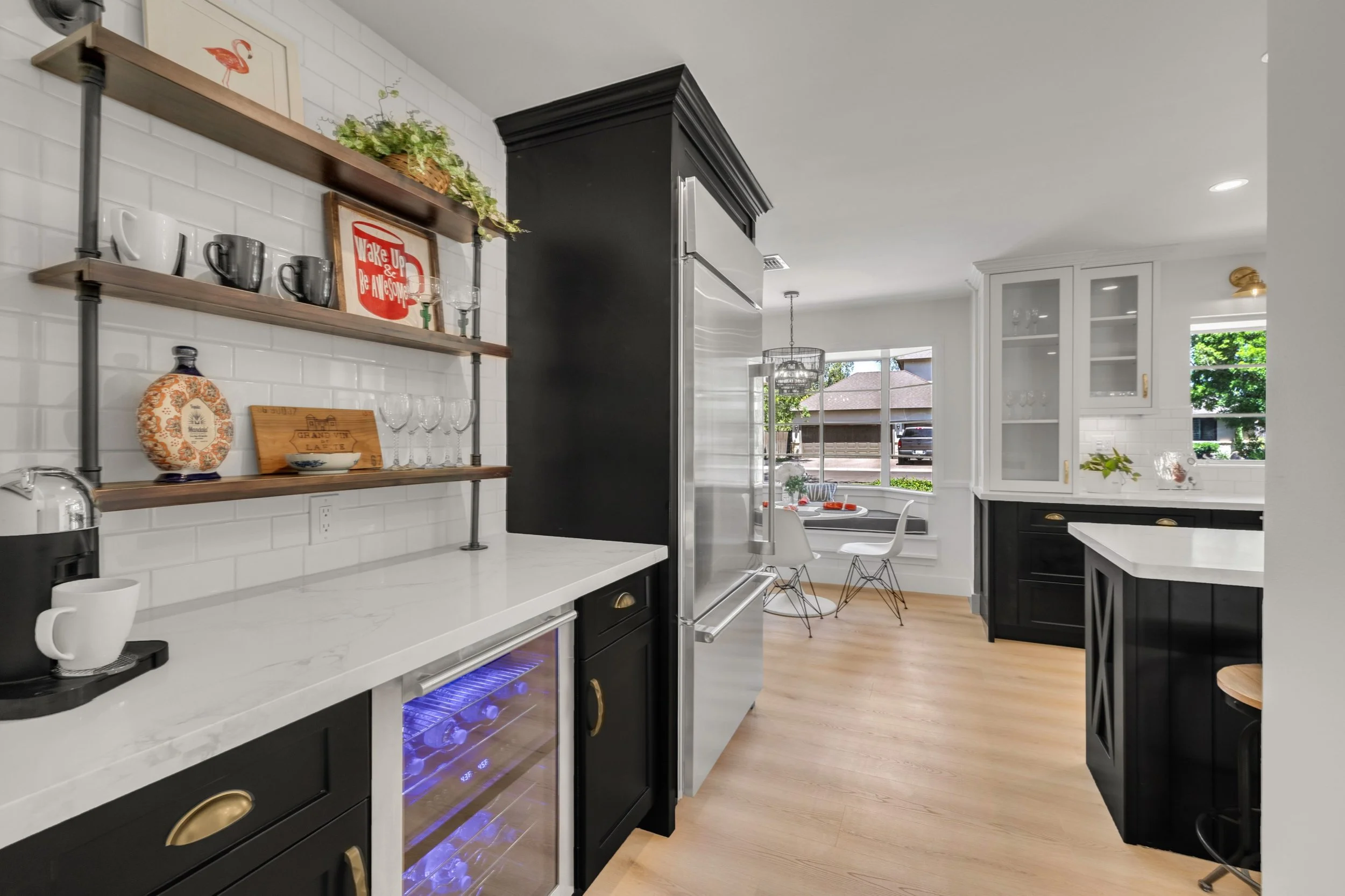 This modern kitchen in Phoenix, AZ features sleek black cabinetry, white countertops, and a cozy breakfast nook, perfectly captured with expert real estate photography to showcase its inviting design.