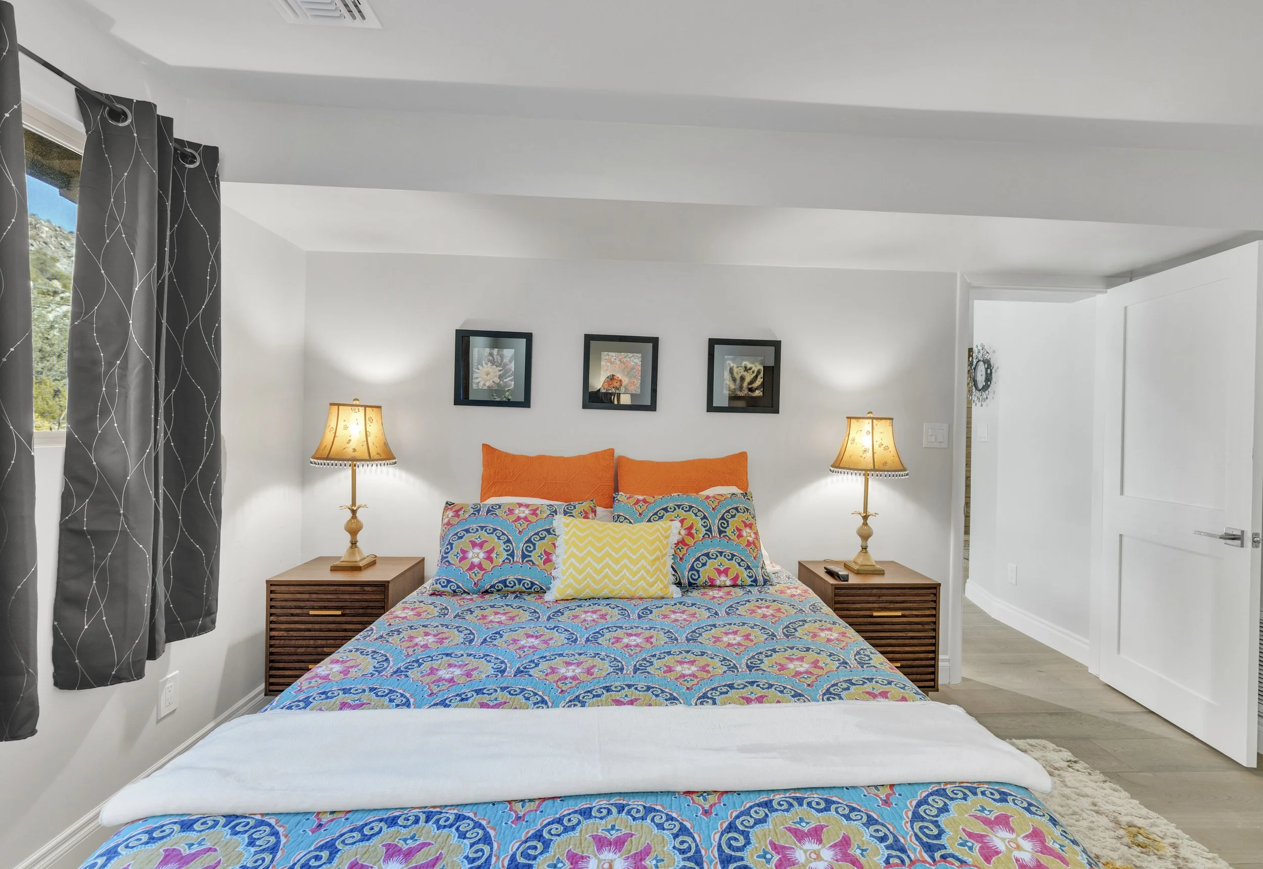 This cozy bedroom in Paradise Valley, AZ features vibrant bedding, stylish lamps, and framed artwork, captured with professional real estate photography to highlight its inviting atmosphere.