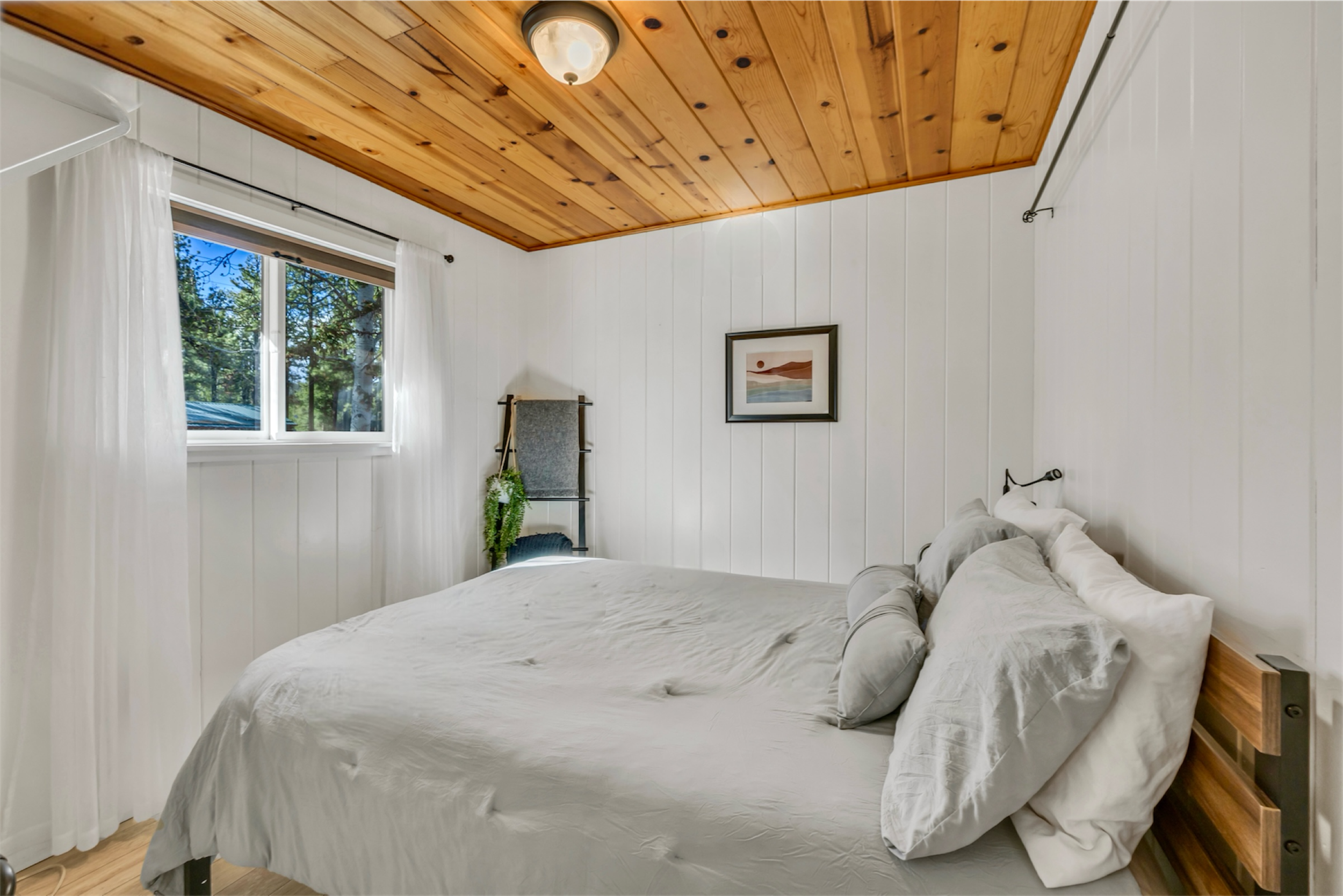 This bedroom in Greer, AZ features a warm wood ceiling and white paneled walls, captured with quality real estate photography to showcase the cozy and inviting interior space.