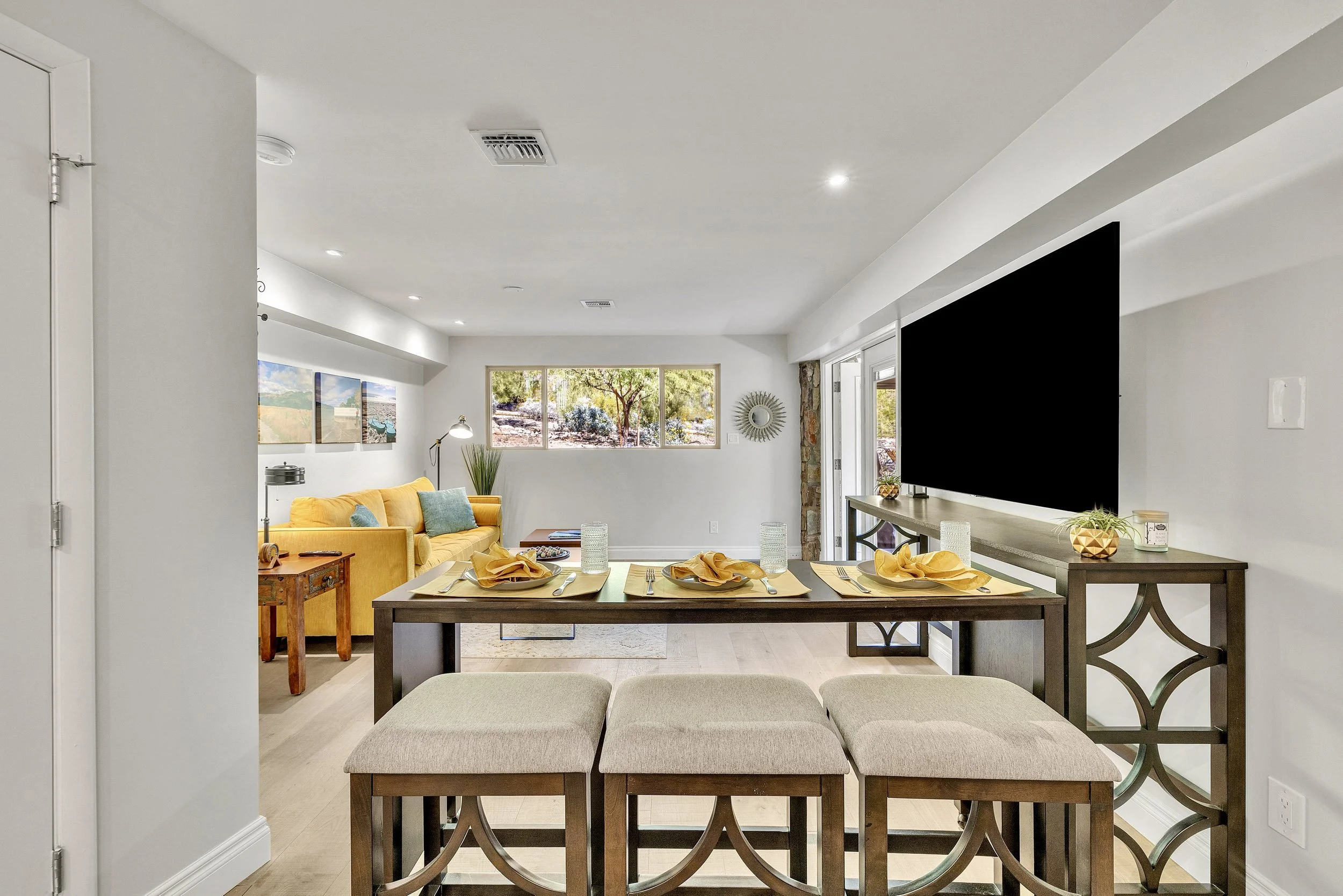 This spacious living room and dining area feature an open layout with modern furnishings, bright natural light, and vibrant decor in a Paradise Valley, AZ home, captured with professional real estate photography.