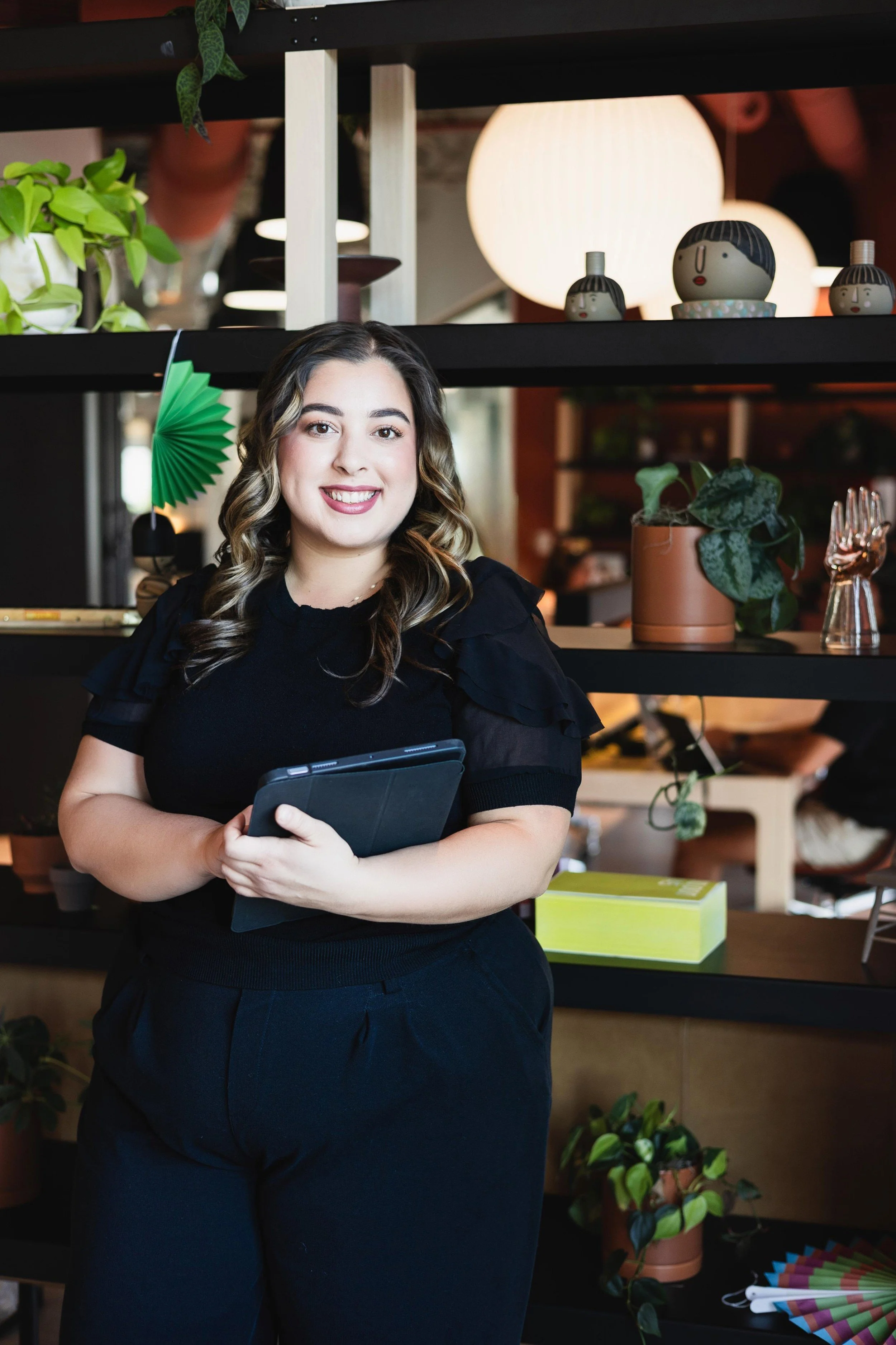 Indoor studio portrait with a smiling woman dressed in black attire, captured in lifestyle branding photography style in East Valley, AZ.