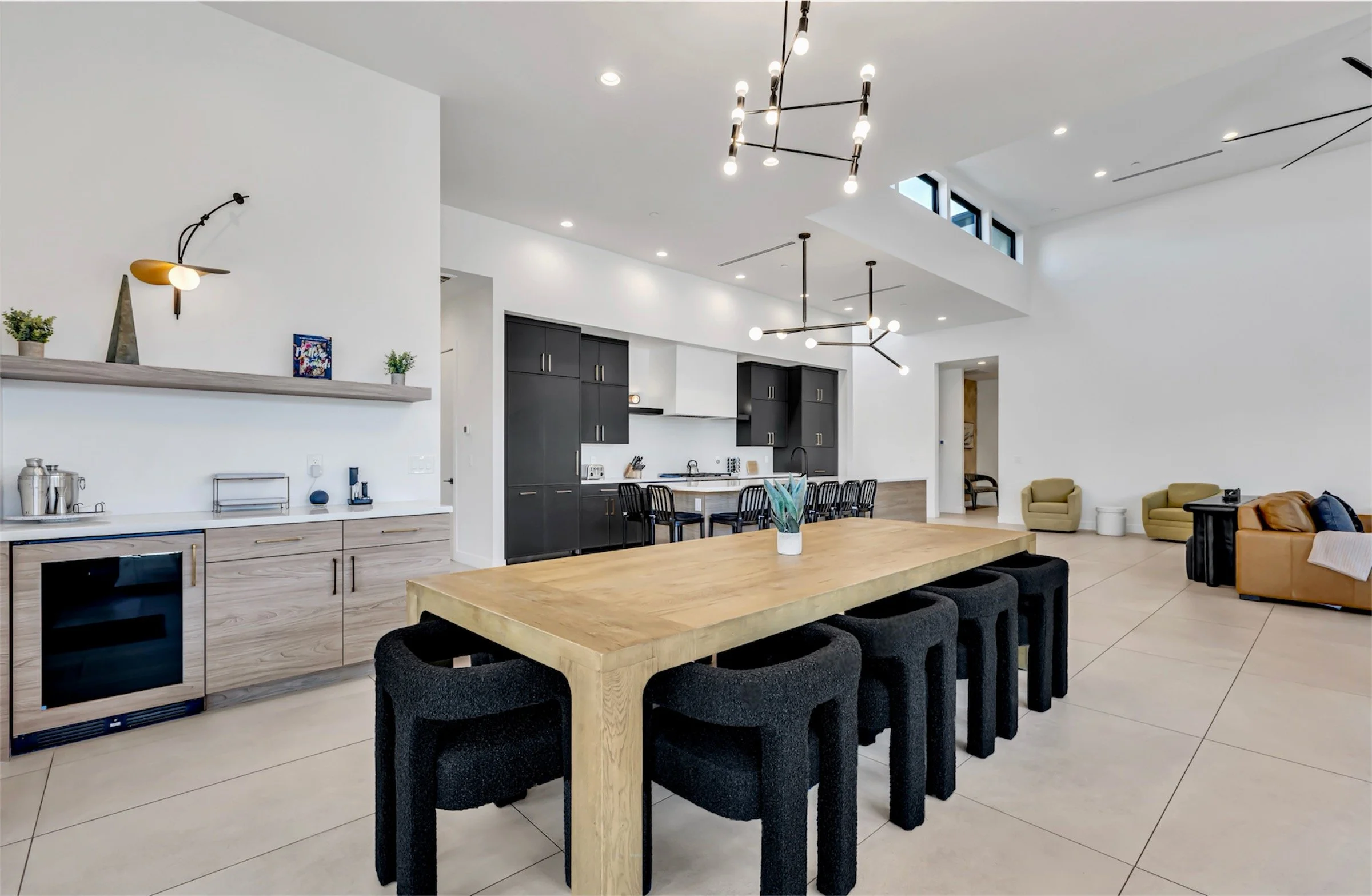Open-concept kitchen and dining area featuring a long wood table, modern lighting fixtures, and sleek cabinetry in Scottsdale, Arizona.