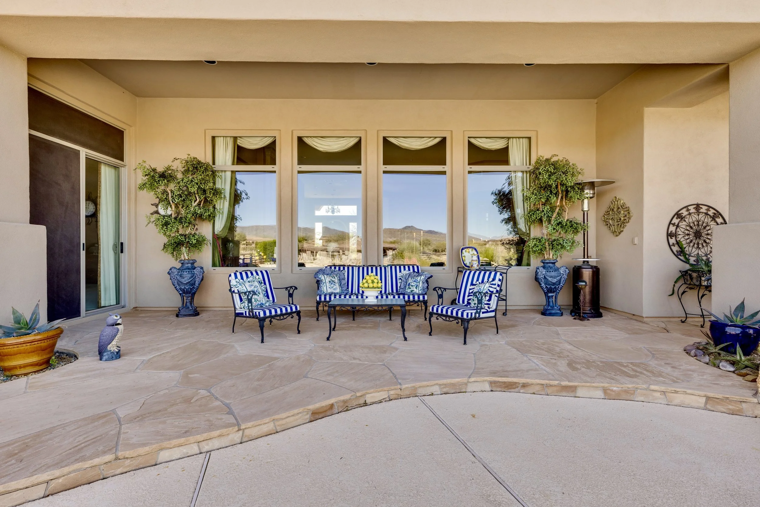 Enjoy the covered patio with blue-striped outdoor furniture in this Scottsdale, AZ home, captured beautifully in this real estate photography image.