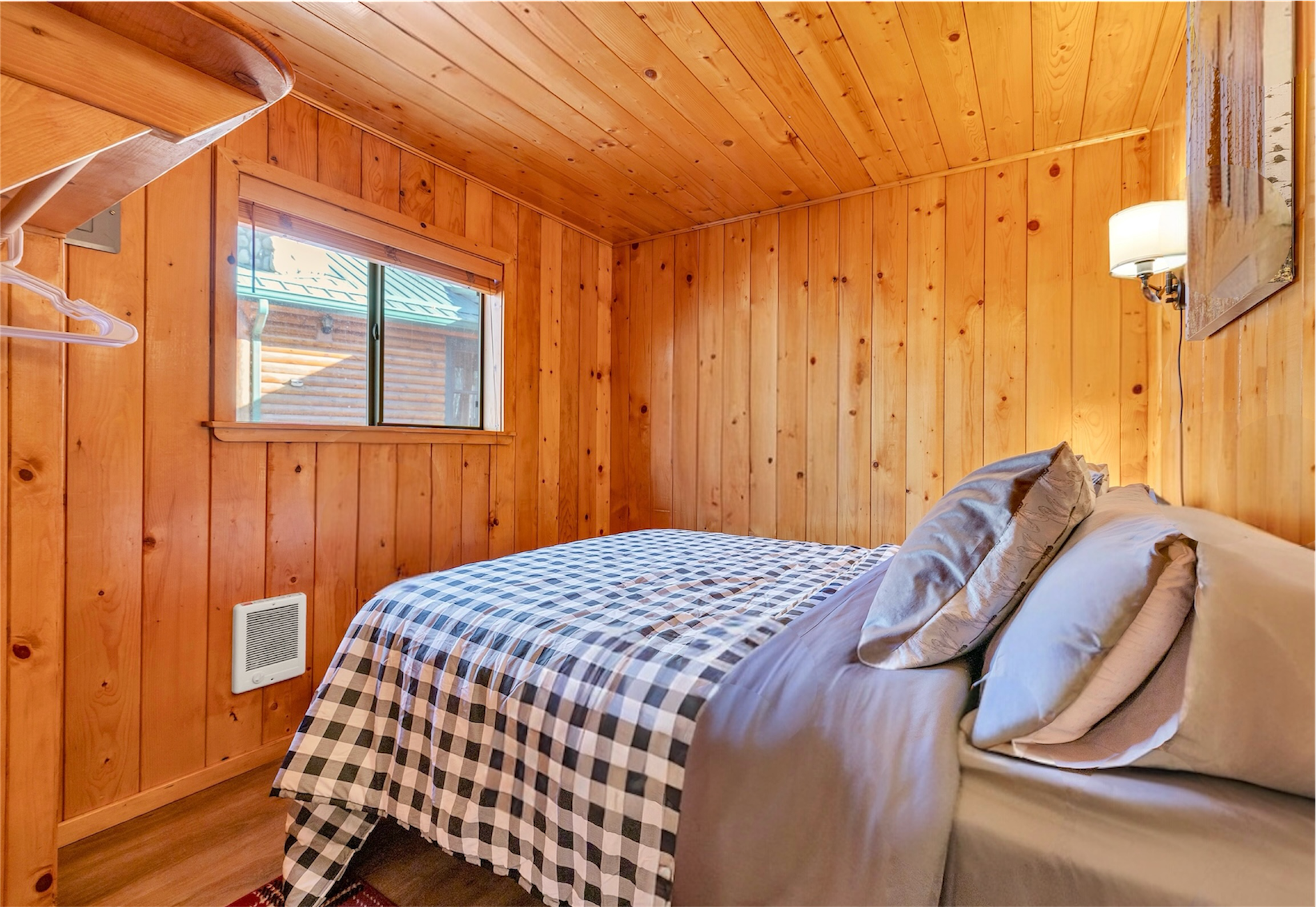 This cozy wood-paneled bedroom in Greer, AZ features a comfortable bed and warm lighting, showcasing rustic charm through expert real estate photography.