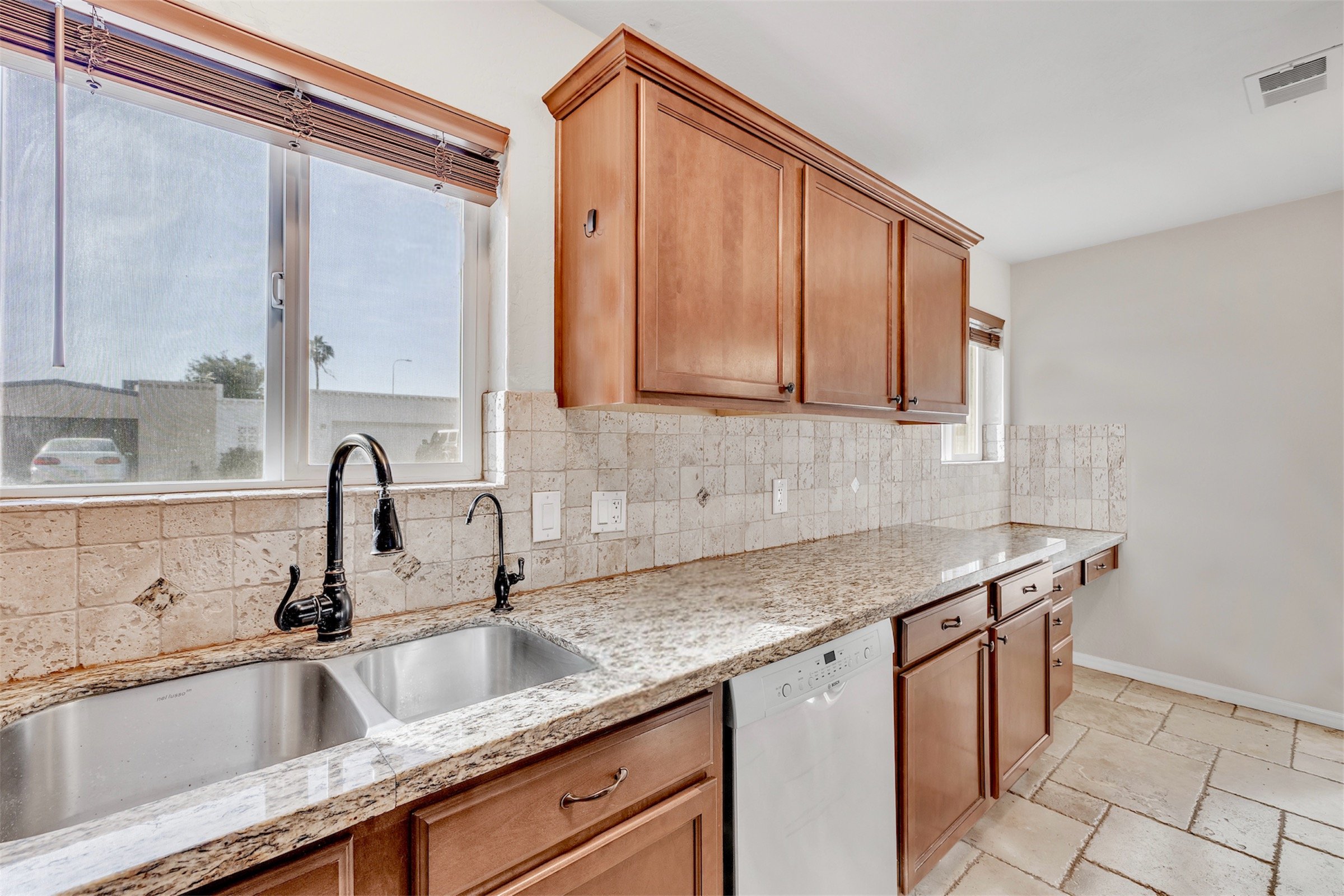 Bright kitchen with granite countertops and wooden cabinets captured through professional real estate photography in Tempe, AZ, showcasing a modern and clean cooking space.