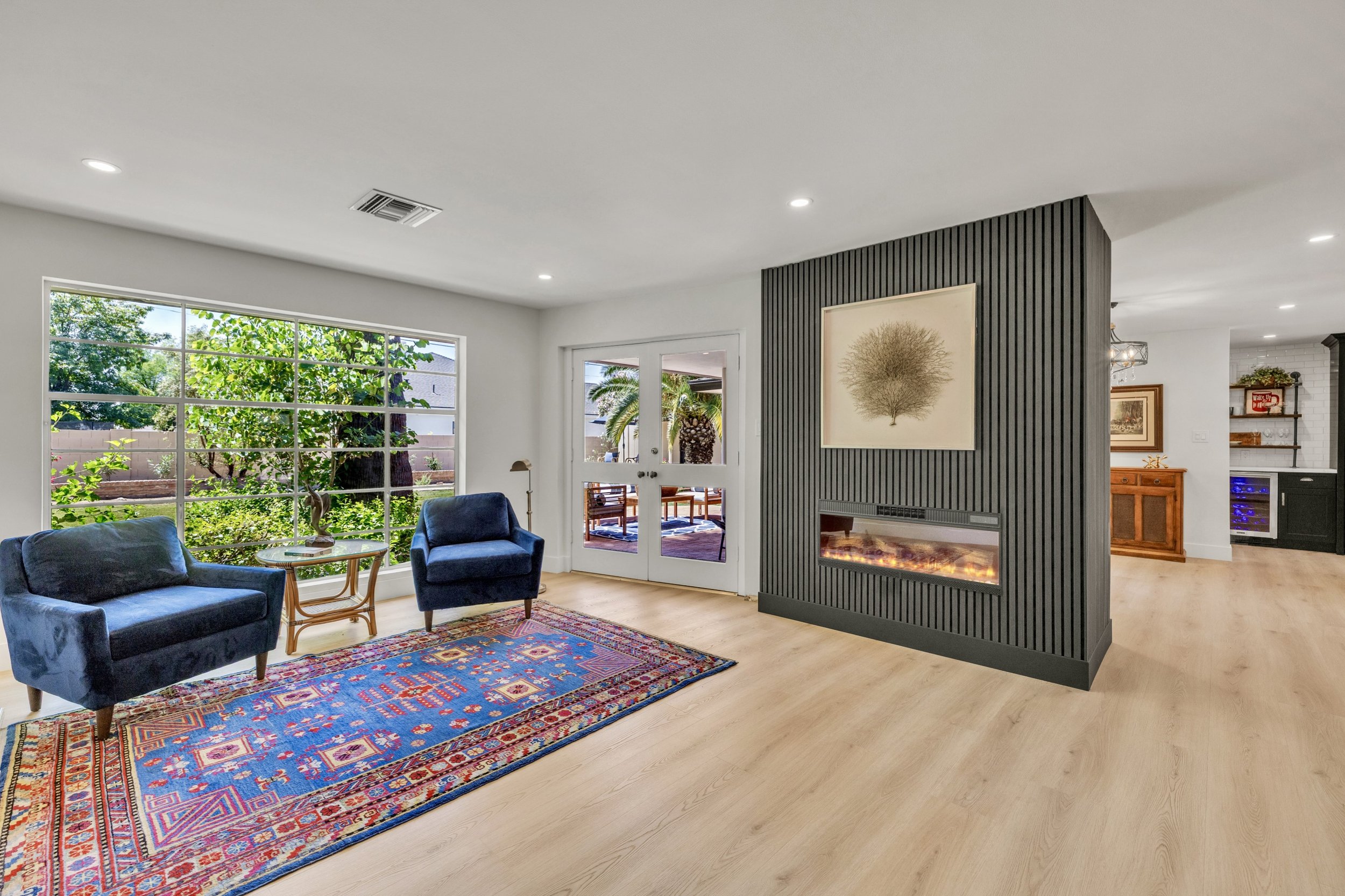 This Phoenix, AZ living room features modern electric fireplace, large windows, and stylish seating, captured through expert real estate photography to showcase bright, inviting interior spaces on E Northview Ave.