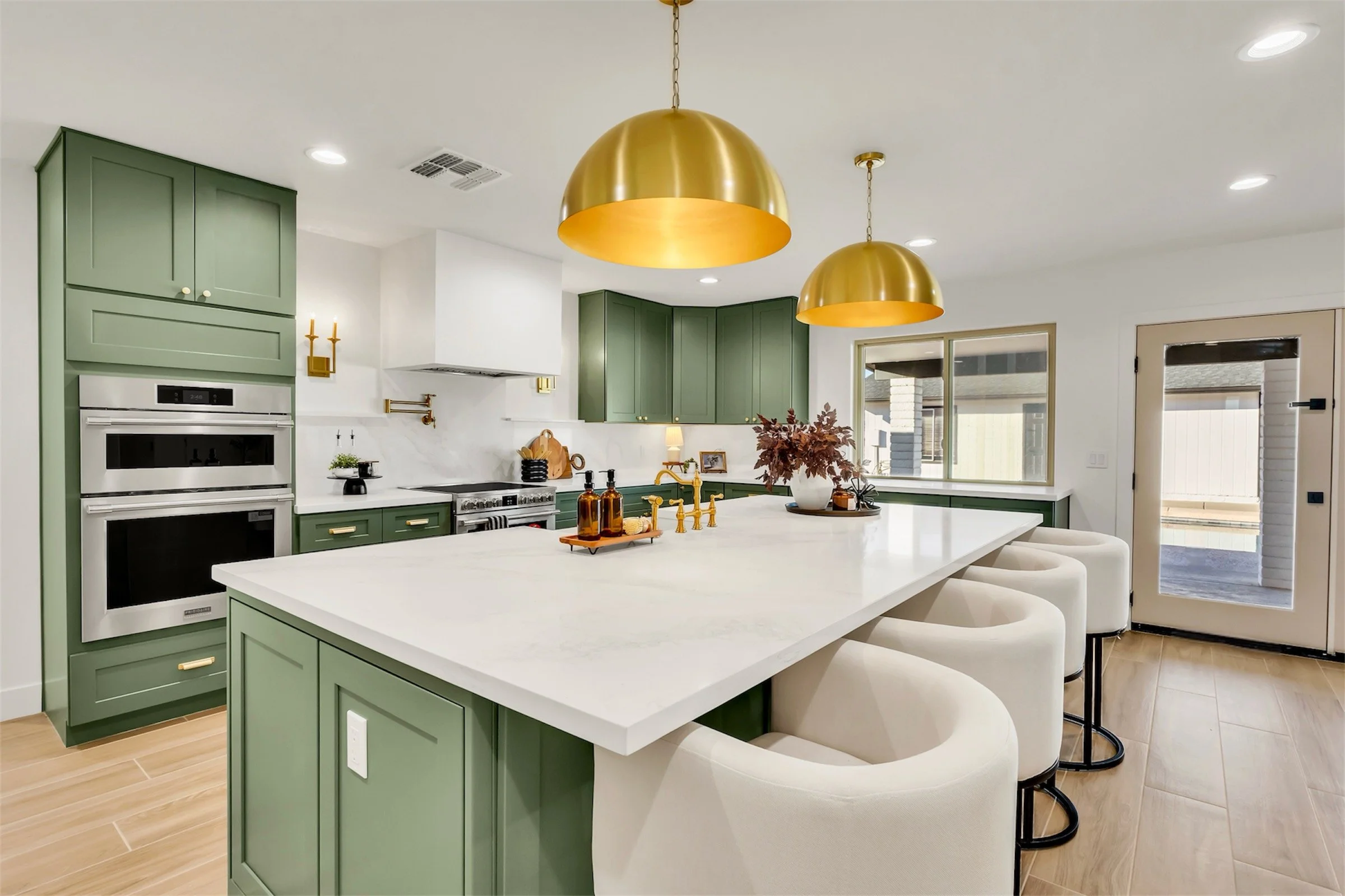 Kitchen range view in Phoenix, AZ showing built-in oven, gold pot filler, and stylish green cabinetry.