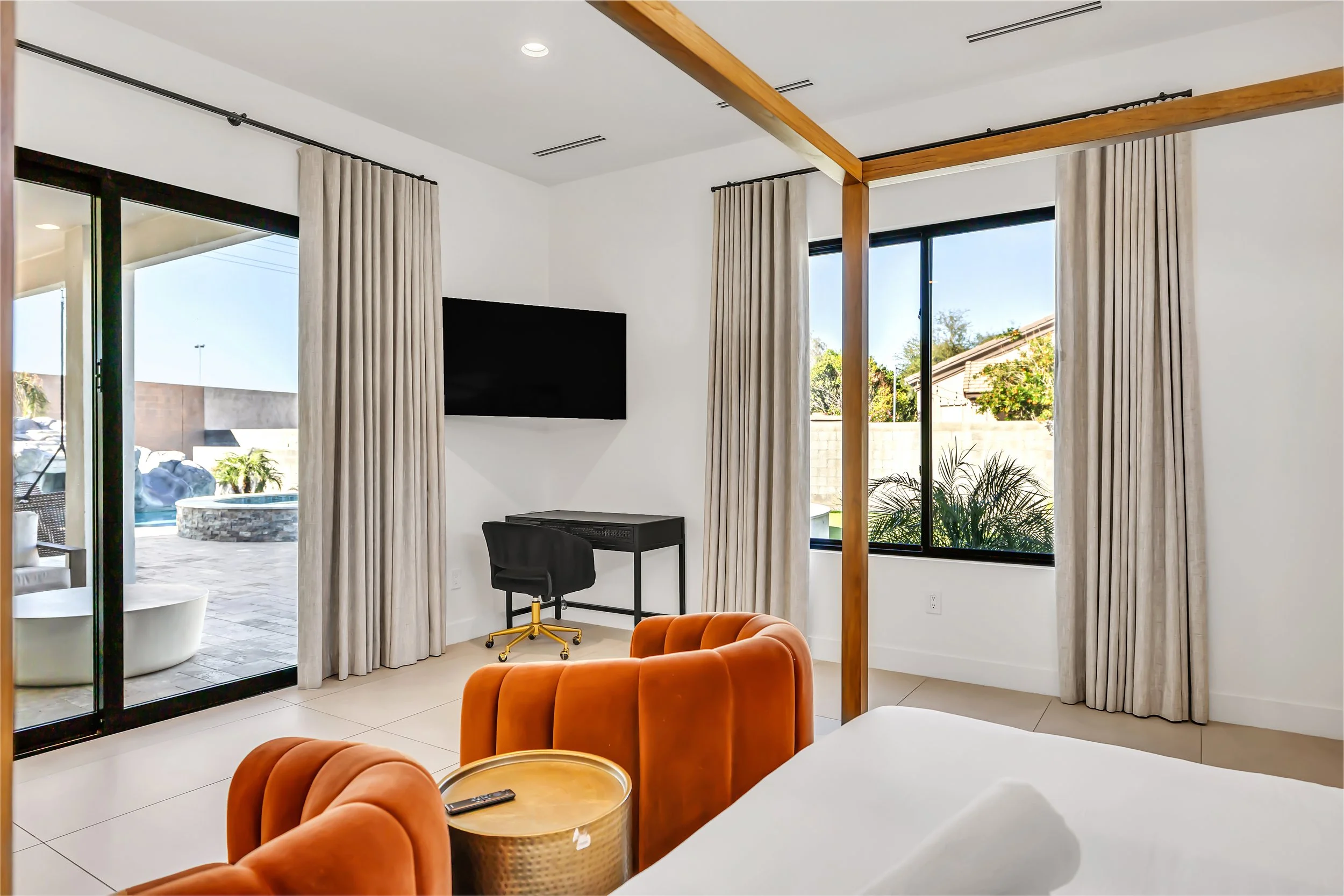 Close-up view of the primary bedroom seating area with two orange accent chairs and large windows in Scottsdale, Arizona.